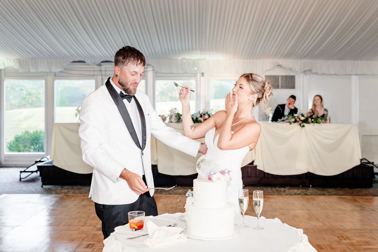 Bride and groom cut their white wedding cake together during the reception in an elegant tented venue.