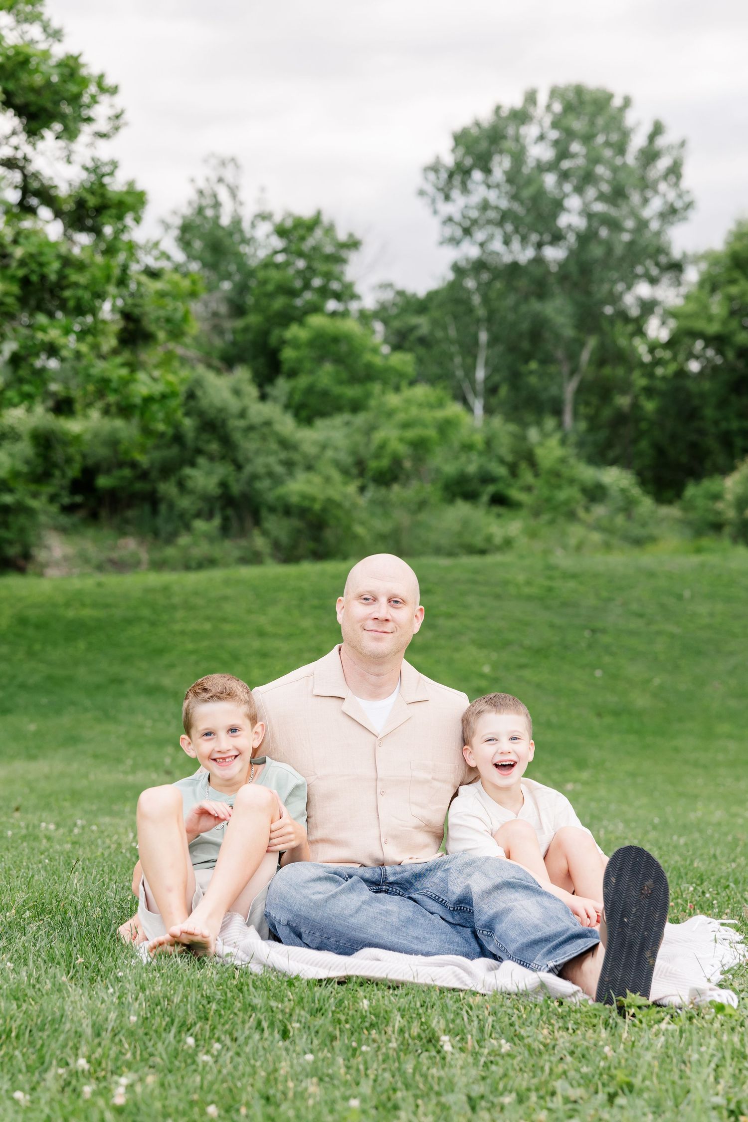 Dad sitting on a blanket with his two sons during a natural family photo session in Crystal Lake.
