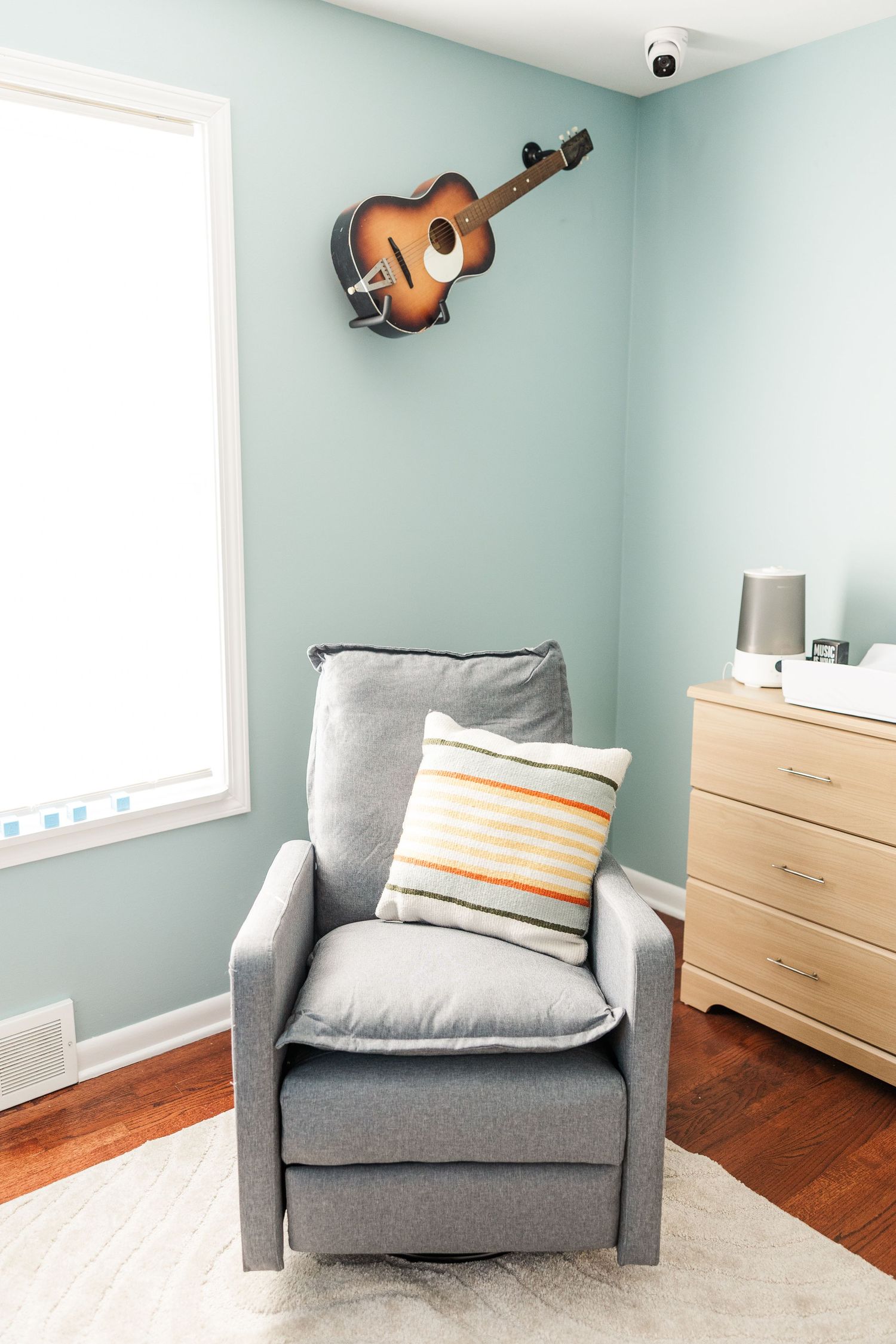 Guitar hanging above nursery chair during a music-inspired in-home maternity session in Crystal Lake, Illinois.