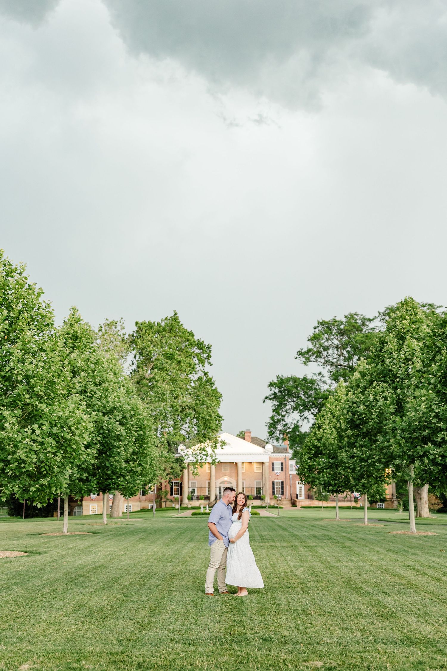 Expecting parents standing beneath stormy skies during a Cantigny Park maternity session