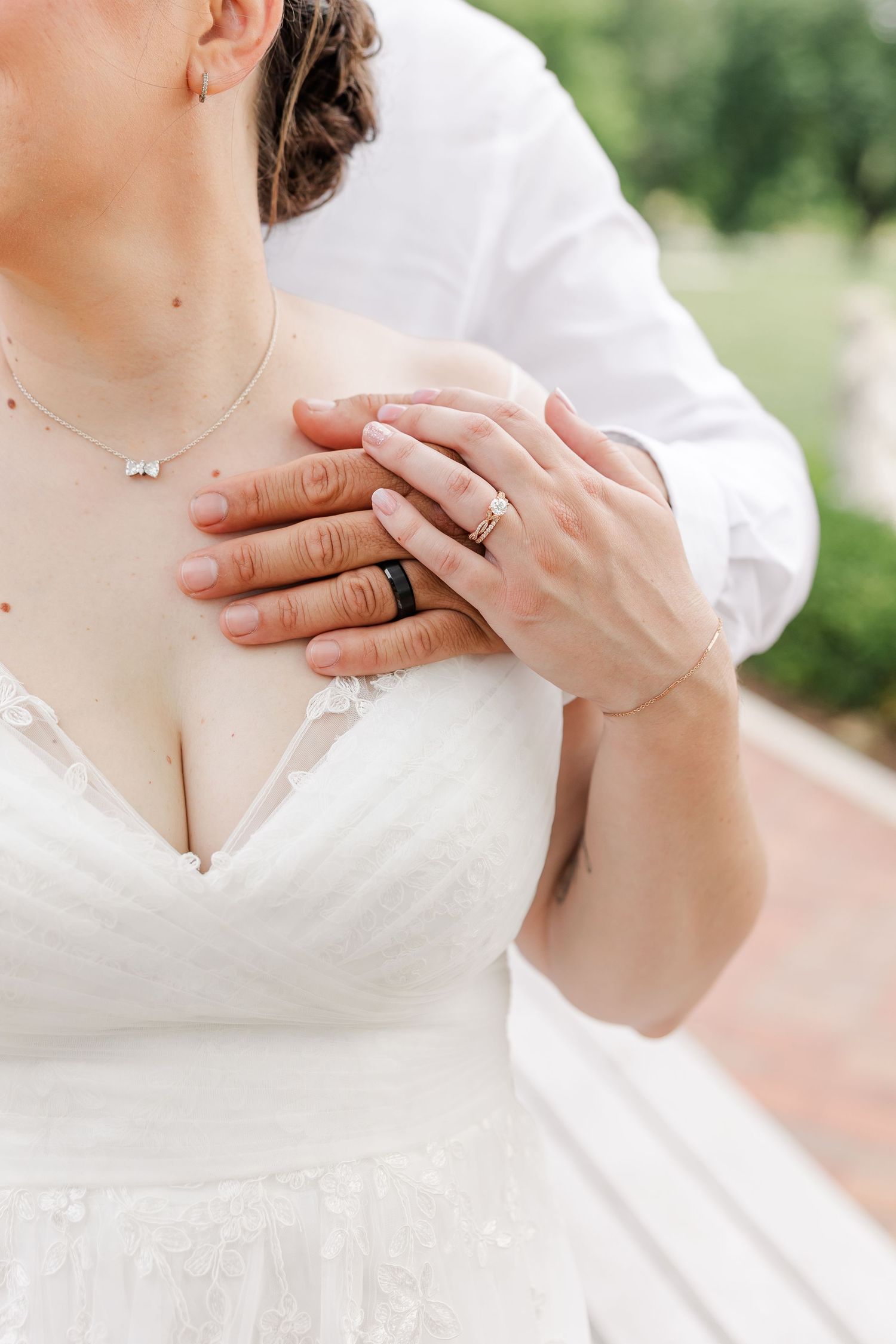 Close-up of Monika and Rafael’s hands displaying their wedding rings against her white wedding dress.