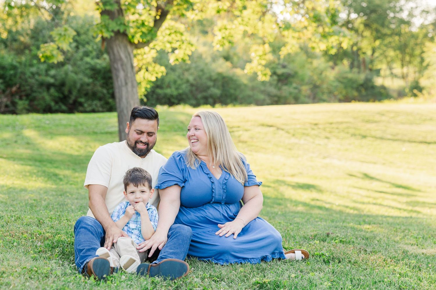 A family sits together on green grass during a sunny outdoor photoshoot at sunset.Sorg family portraits at Shamrock Hills Park in Crystal La