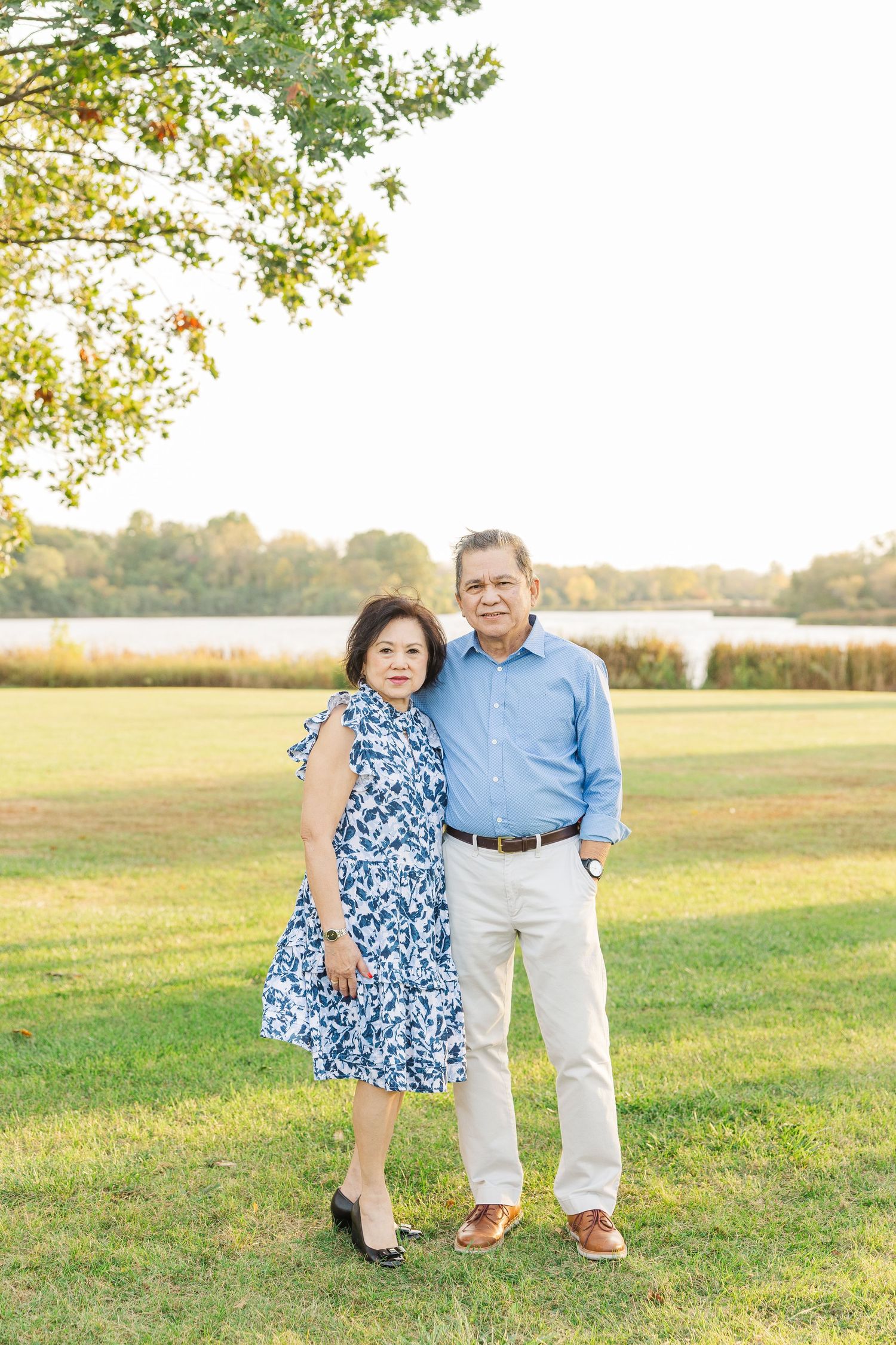 A pair enjoying a tender moment together in a sunlit grassy field during golden hour. Busse Woods