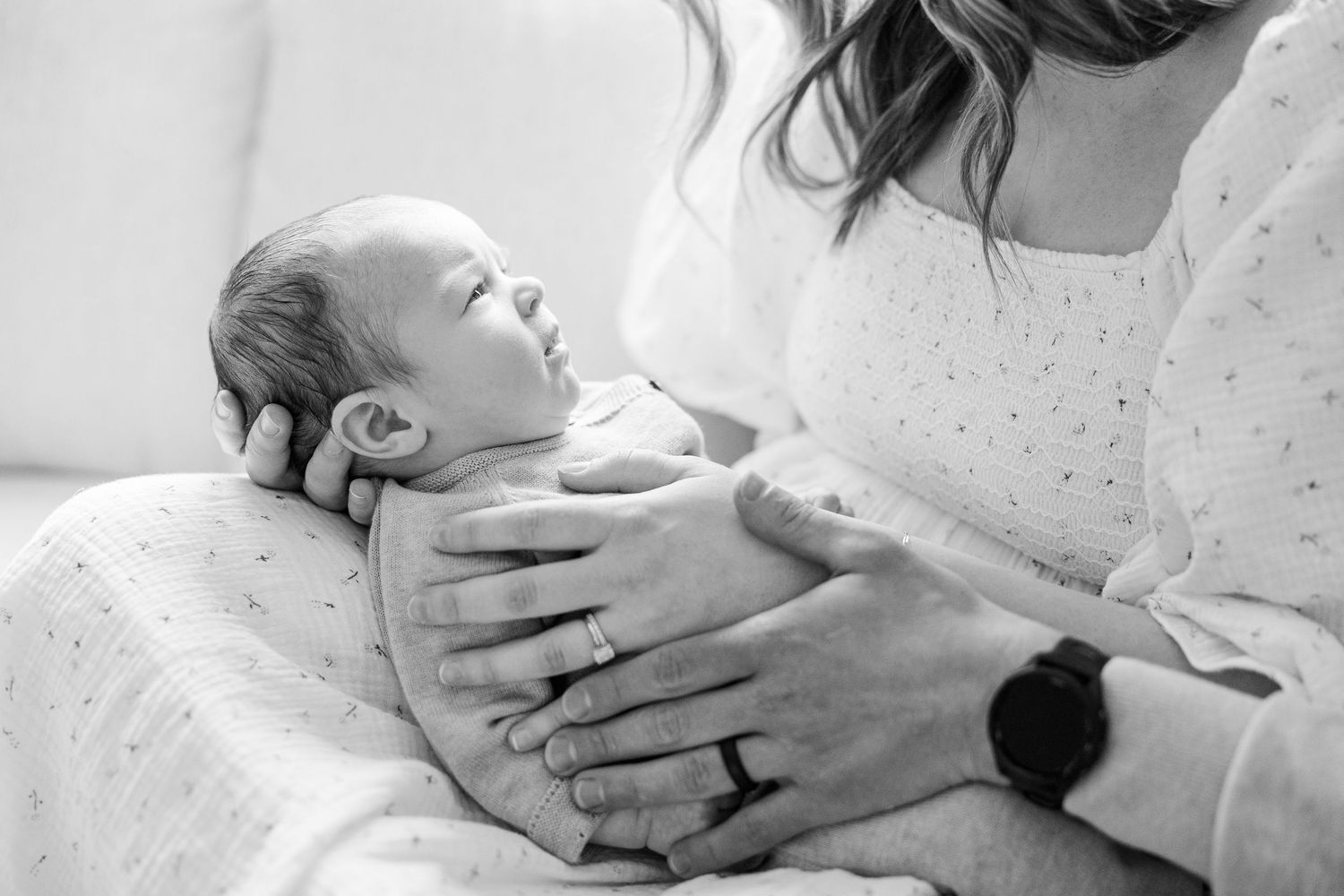 A collection of black and white photographs showing gentle moments of newborn baby care and nursing.