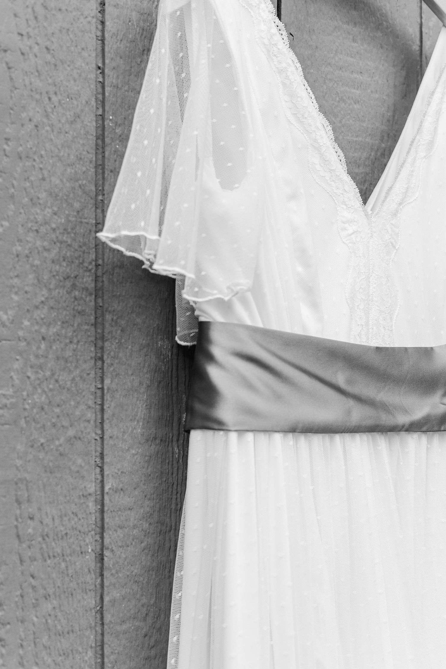 Close-up detail of a white wedding dress showing delicate flutter sleeves and pleated waistband.