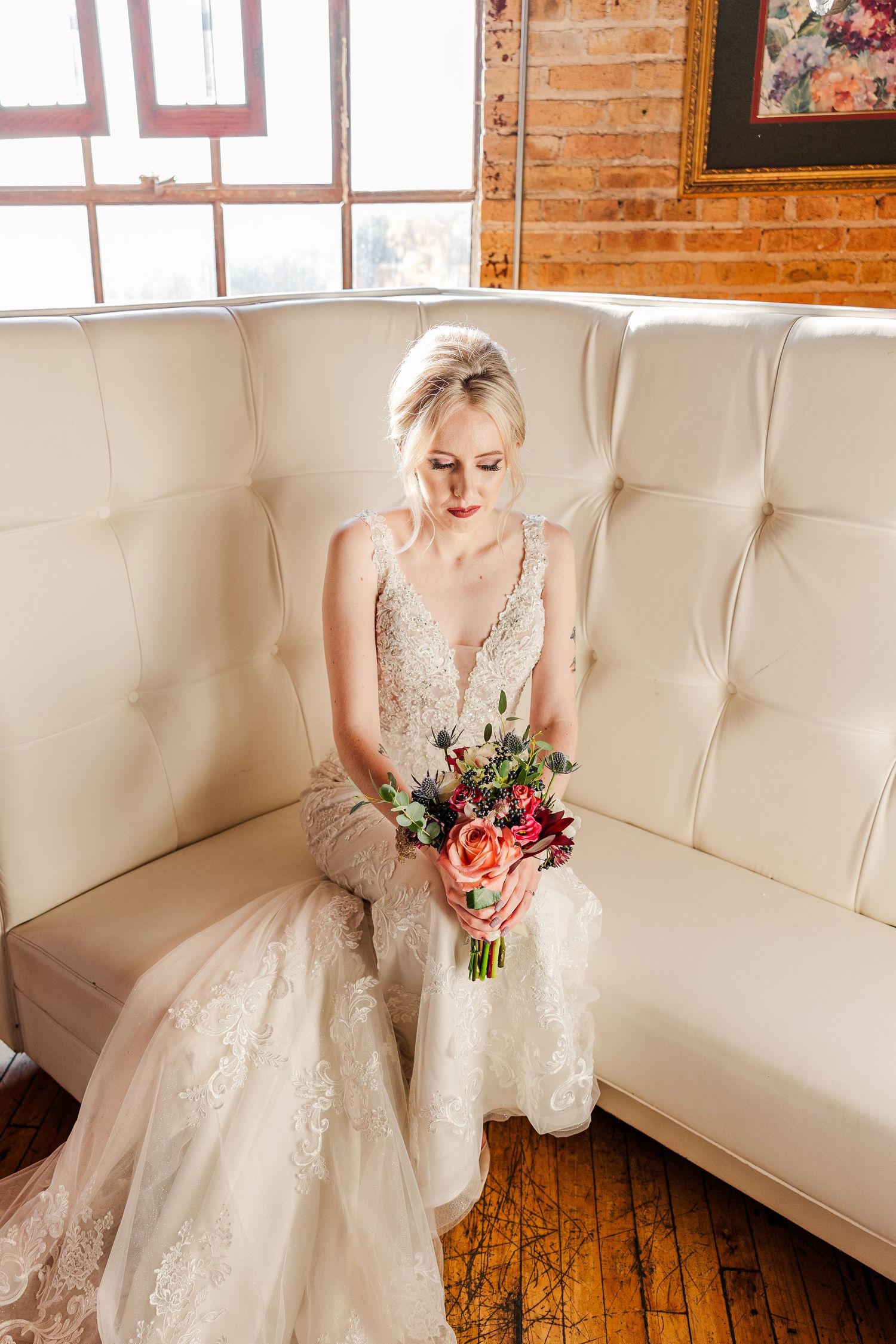 Elegant wedding dress with lace details and flowing train showcased in rustic brick room setting.