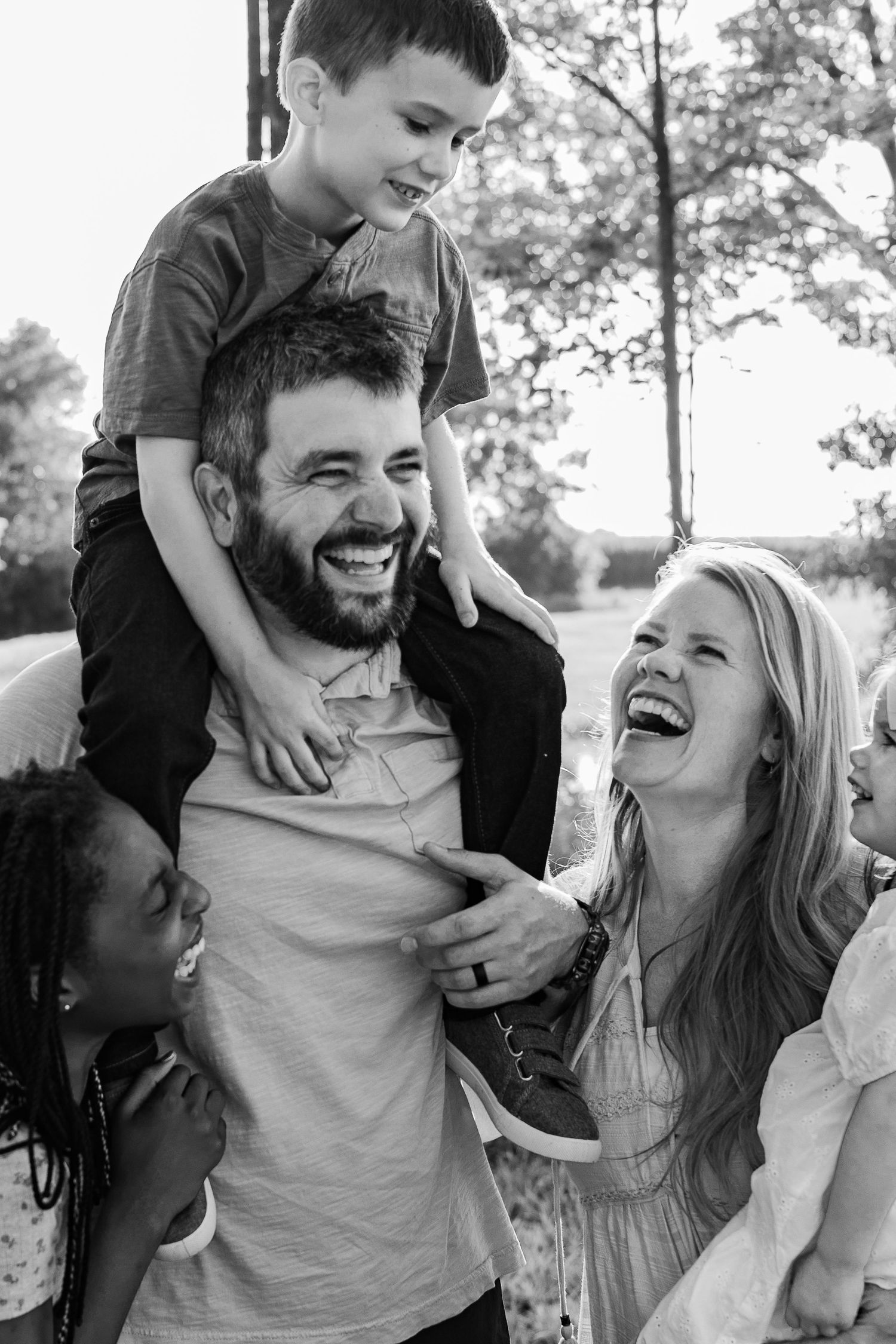 A joyful family moment captured in black and white as they laugh together outdoors.