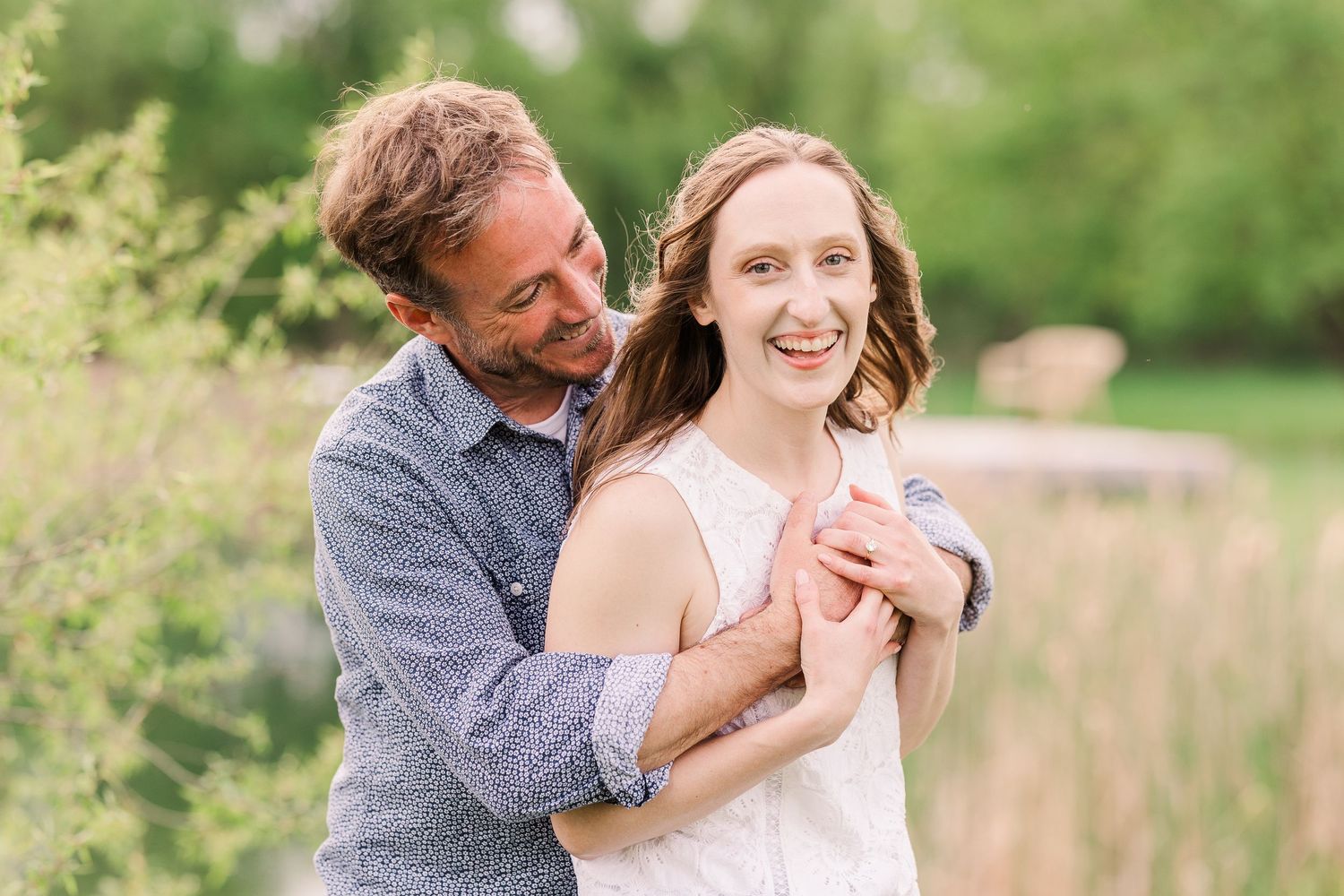 A romantic couple embraces in a springtime field with soft natural lighting.
