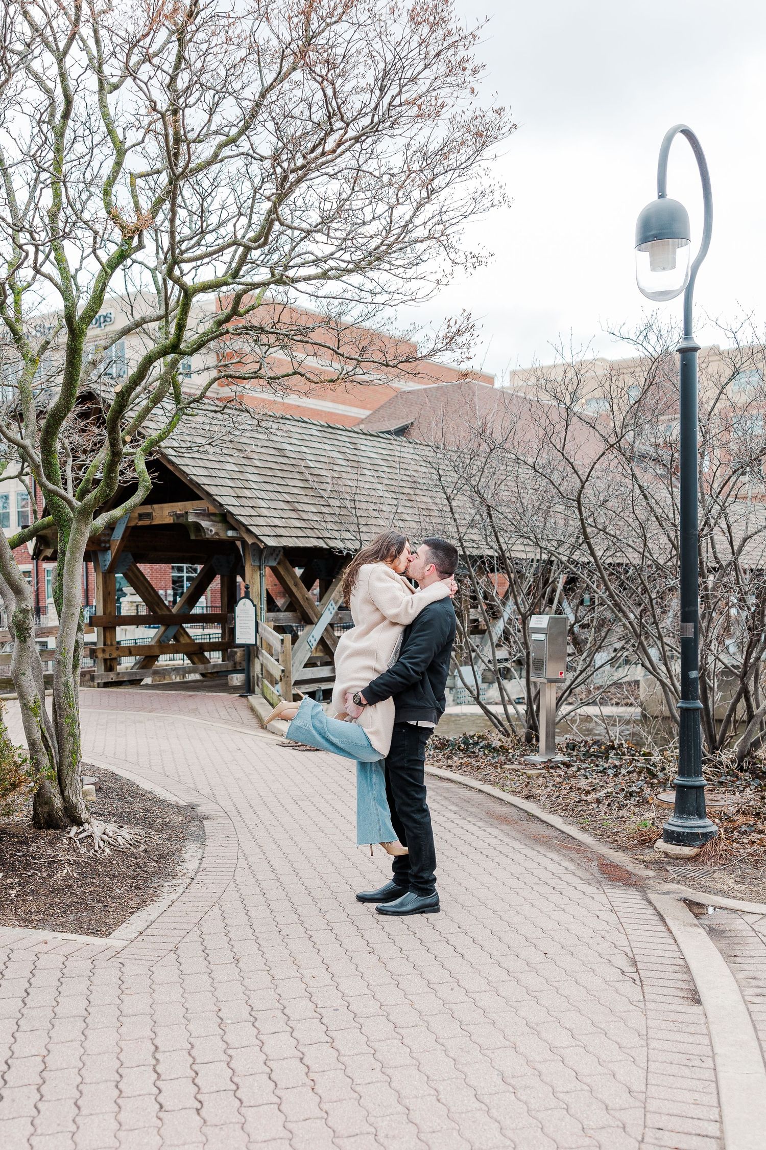 A joyful lift pose captured on a brick pathway with a wooden gazebo in the background.