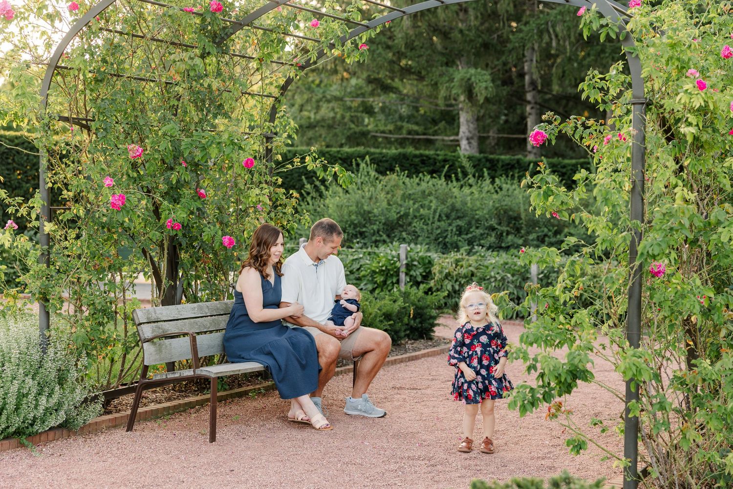 Caroline exploring the garden as Hilary, Andrew, and baby Lincoln sit together nearby.