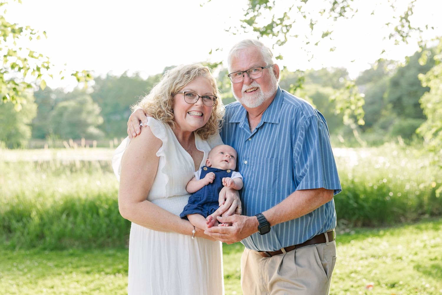 Grandparents holding their baby grandson during a summer extended family session at Veterans Acres Nature Center in Crystal Lake