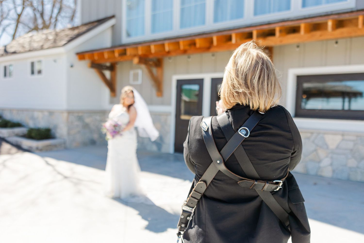 Cassie Lacina photographing a bride outdoors in front of a stone venue