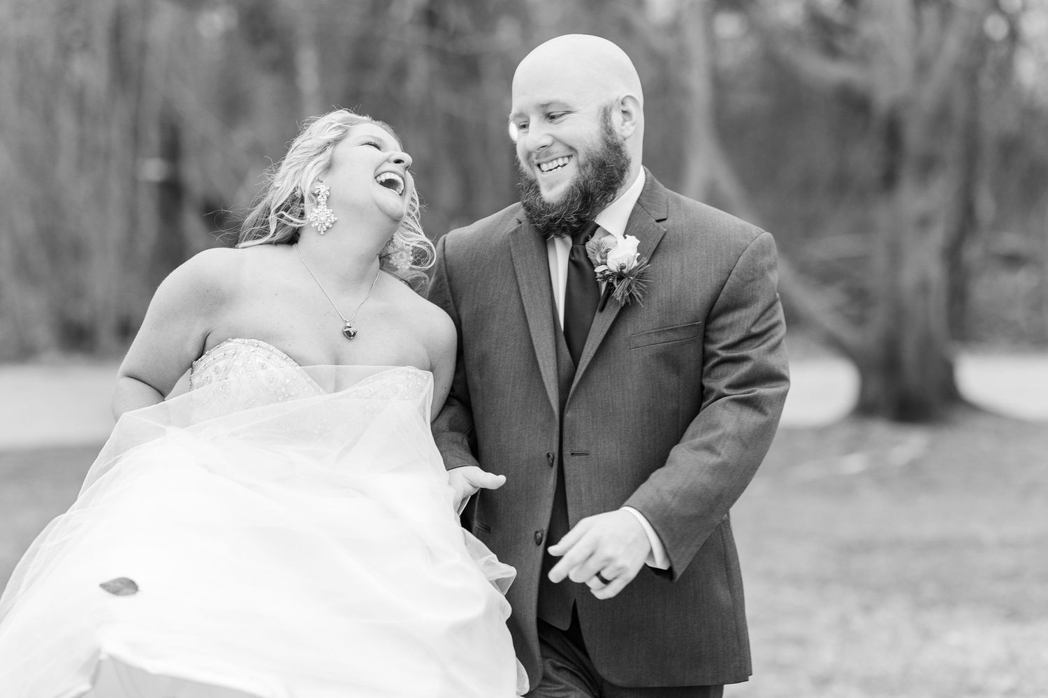 Black and white candid wedding photo capturing genuine laughter between newlyweds.