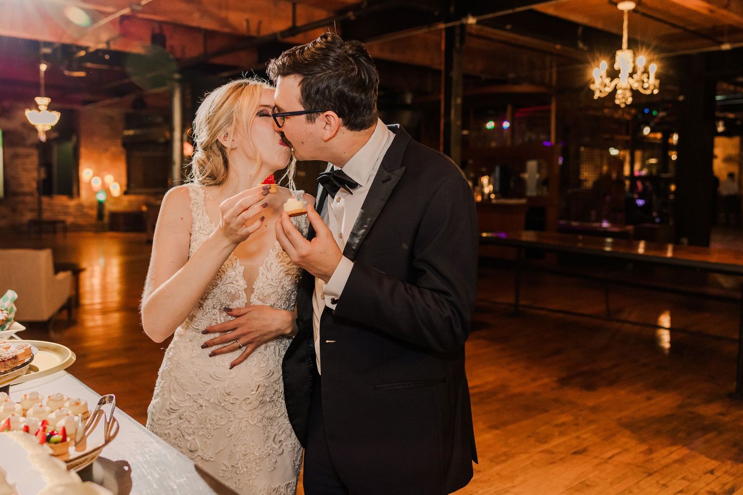 Romantic moment shared at wedding reception dessert table.
