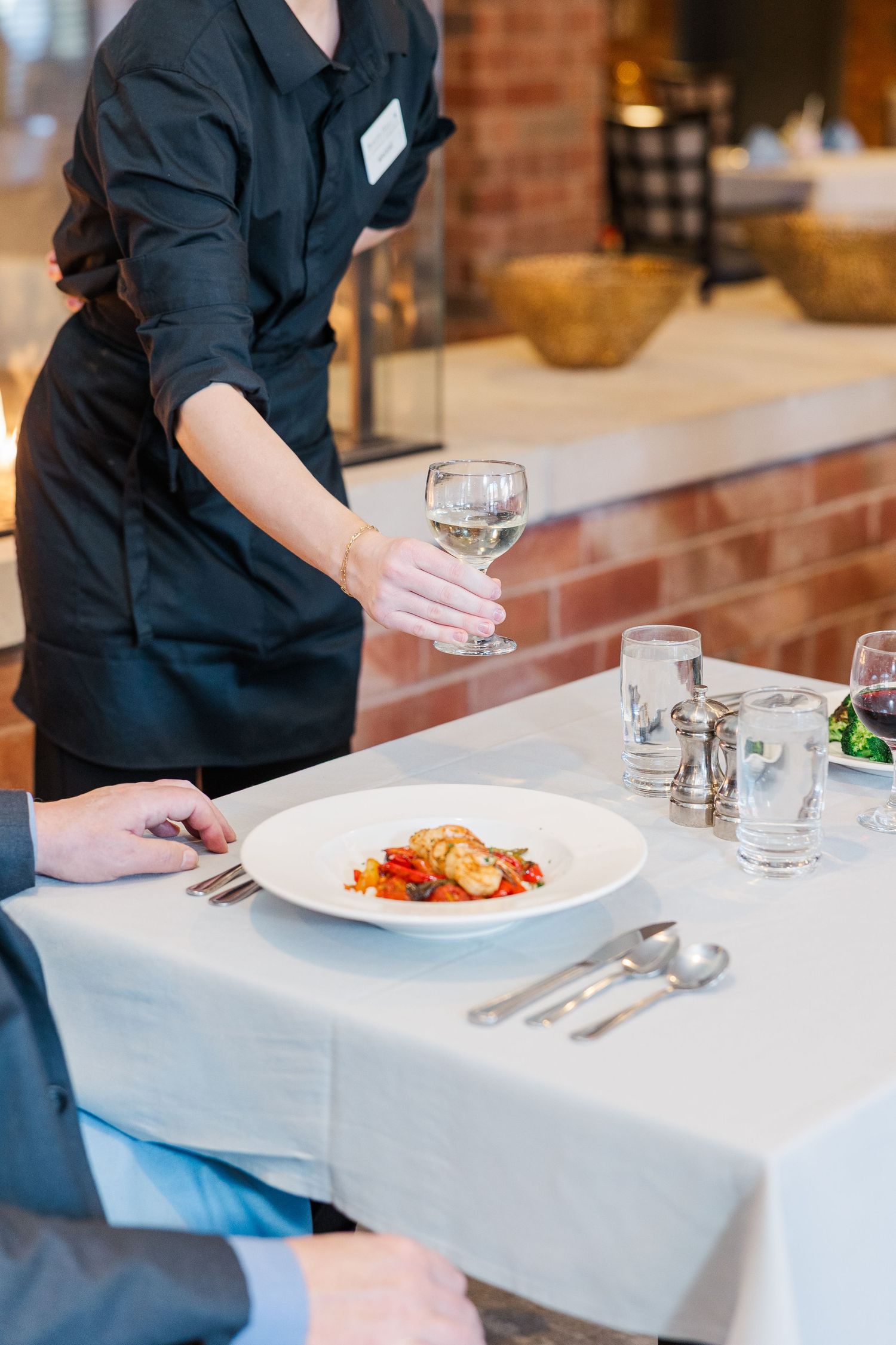 Beacon Hill senior living branding photo in Lombard, Illinois featuring server setting table with plated meal