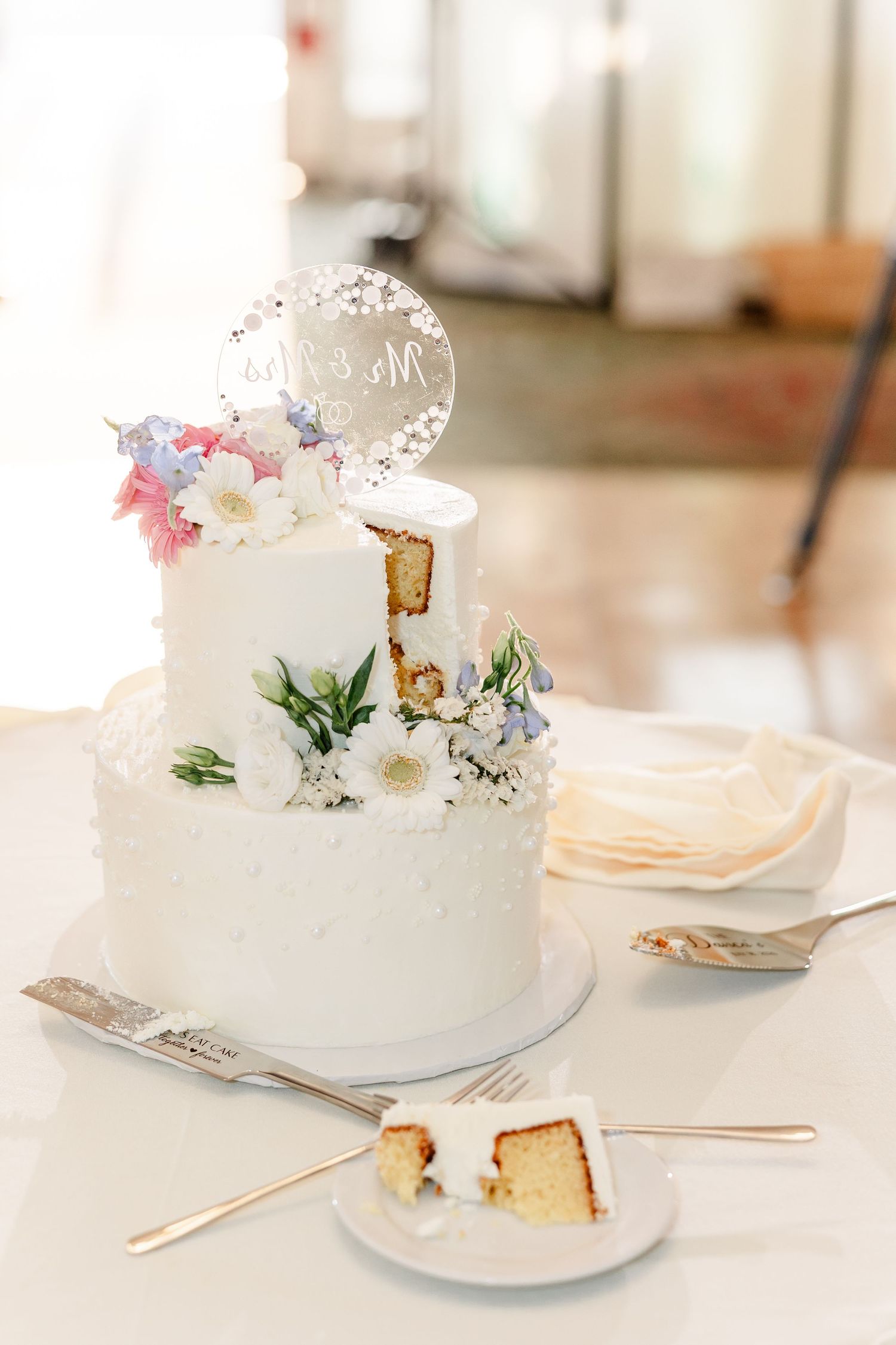 Elegant two-tier white wedding cake with floral decorations and Mr and Mrs cake topper.
