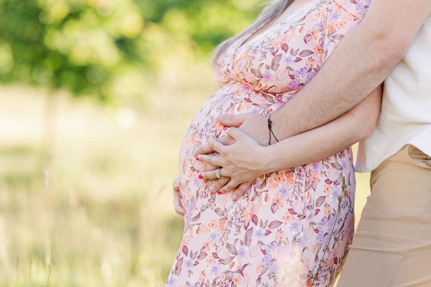 Close-up maternity photo of hands holding baby bump during a Cantigny Park maternity session