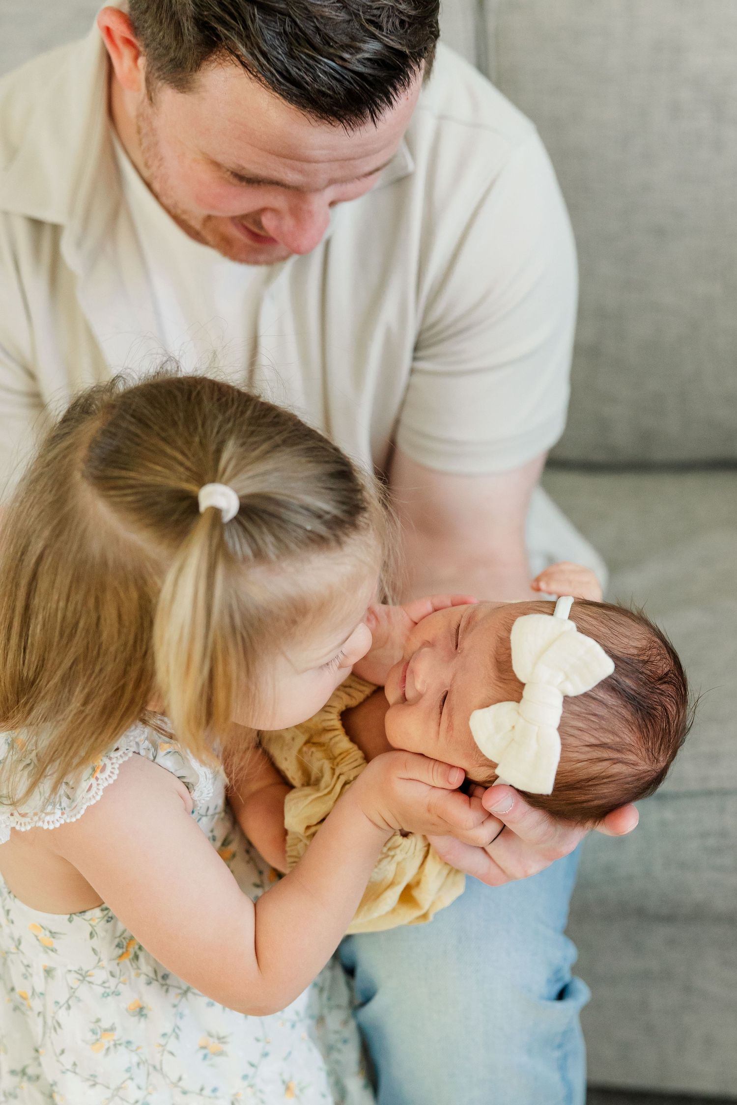 Sweet sibling moment with big sister looking at baby girl during an in-home newborn session