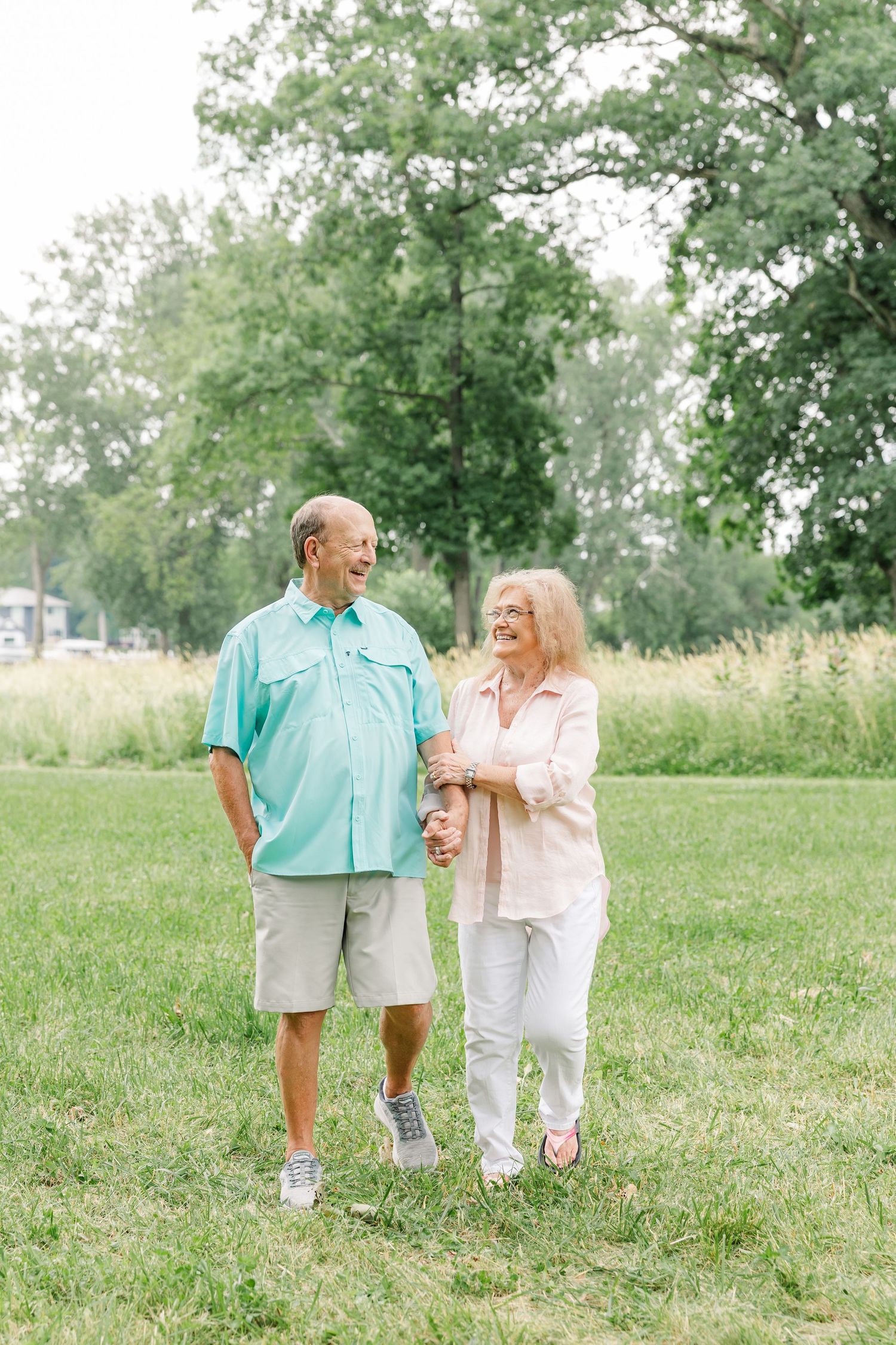 Couple walking together through a grassy yard during a summer family reunion session in Crystal Lake, Illinois.