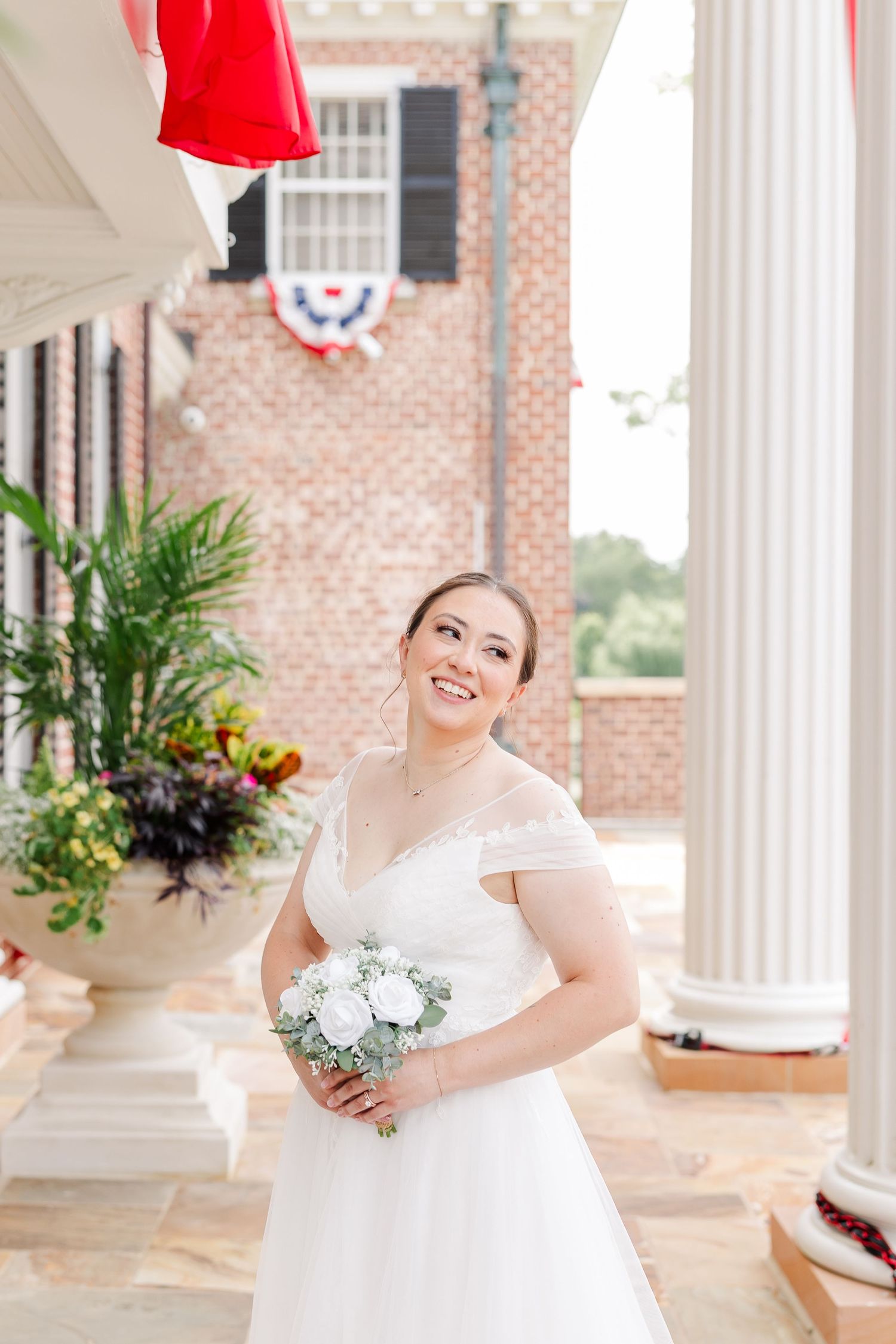 Monika smiling with her wedding bouquet beneath the white columns at Cantigny Park.