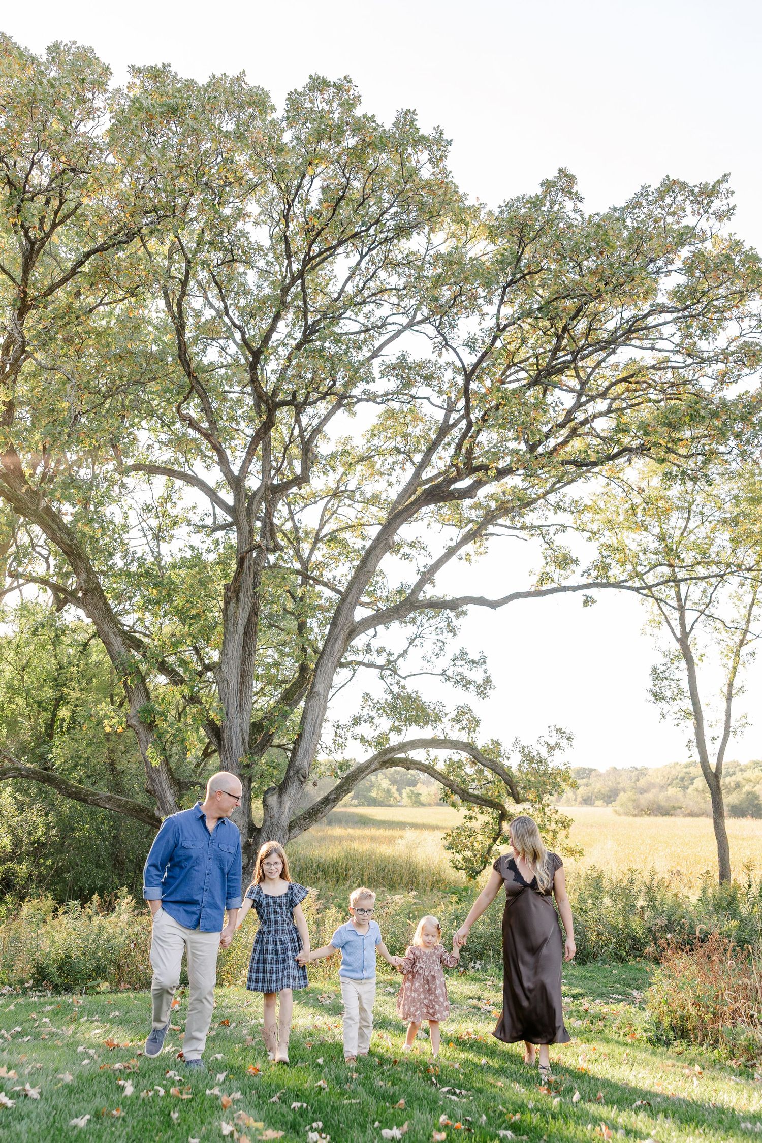 Family of five standing beneath a large tree during backyard family photos in St. Charles, IL.