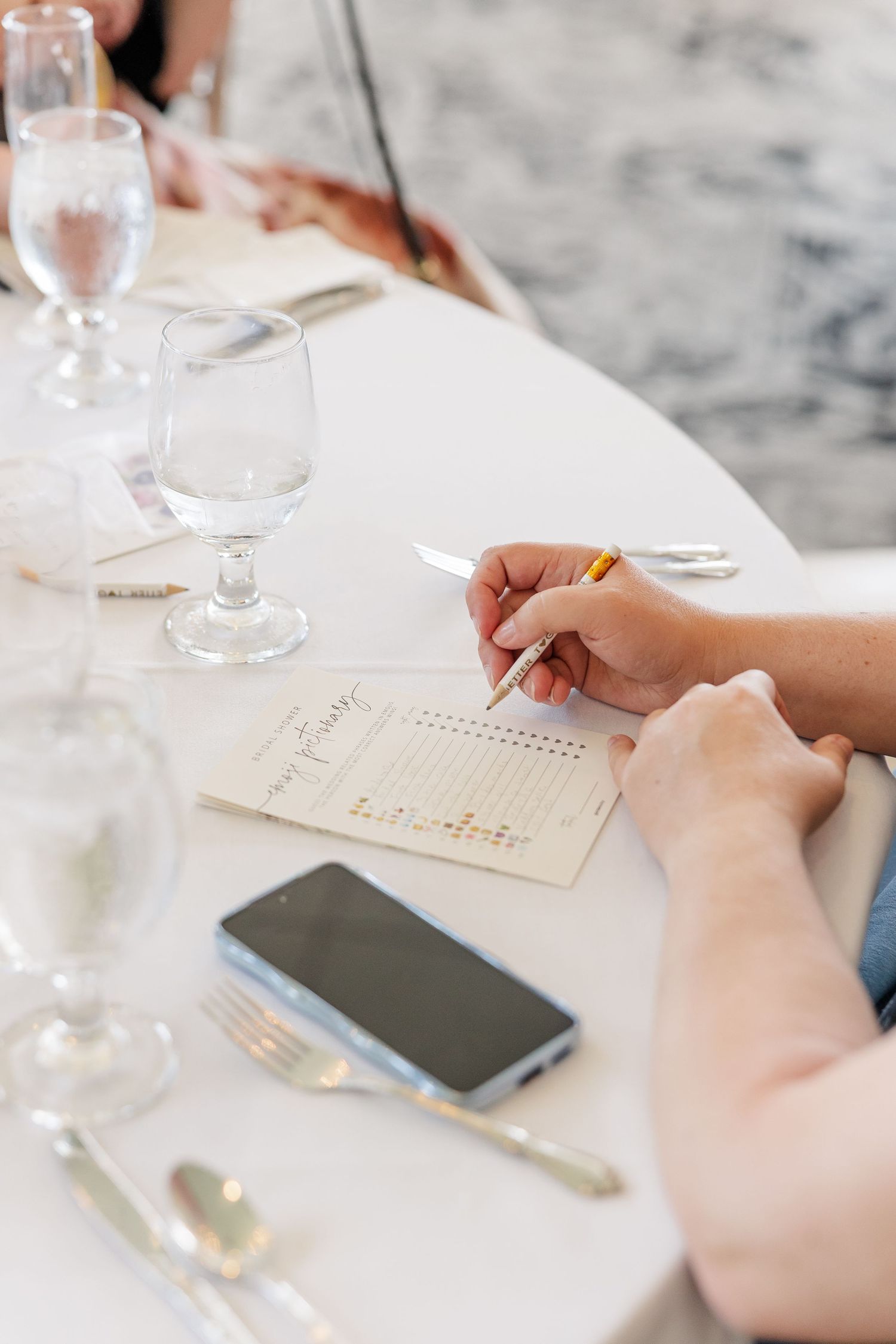 Guest writing advice card with phone on table at bridal shower