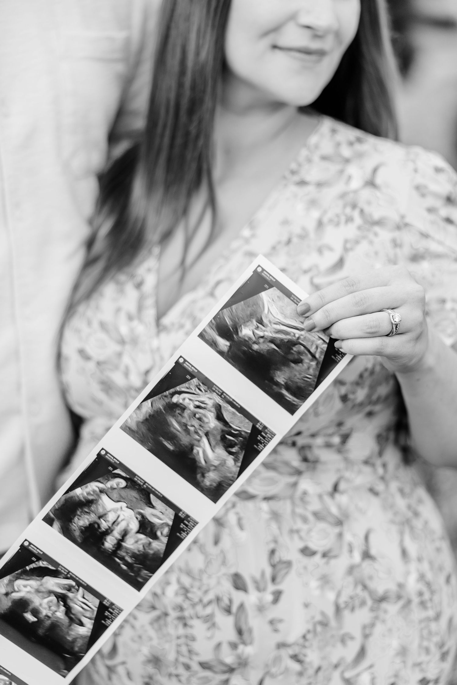 Black and white maternity photo holding ultrasound pictures over baby bump at Cantigny Park in Wheaton Illinois