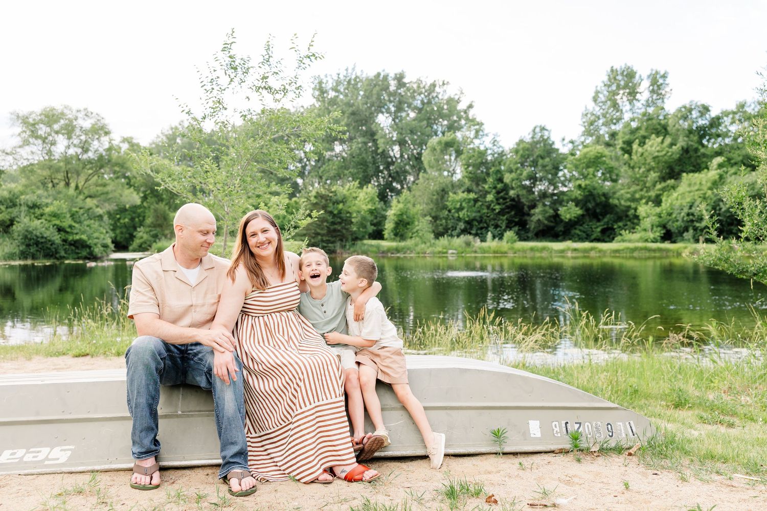 Family of four sitting along the lake during a relaxed Crystal Lake family portrait session at Shamrock Hills Park.