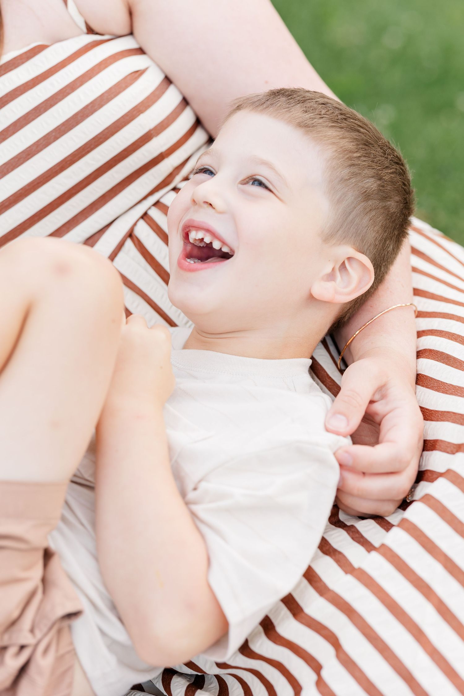 Young boy laughing with his mom during a candid family photo session in Crystal Lake, Illinois.