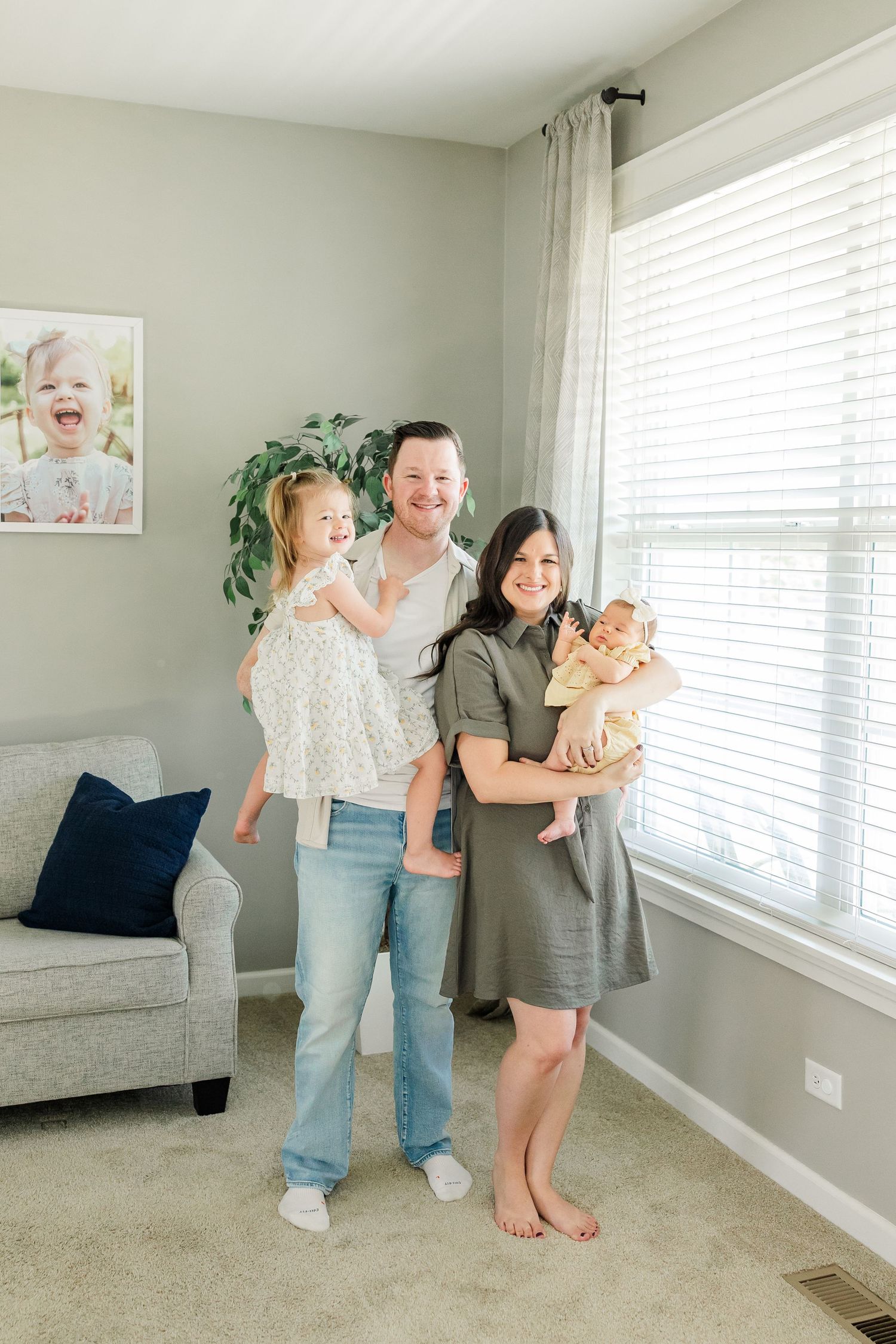 Family standing together near the window during a bright in-home newborn session in Huntley IL