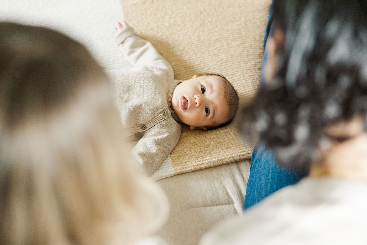 Newborn baby lying on a bed looking up at parents during an in-home lifestyle newborn photography session in Palatine Illinois