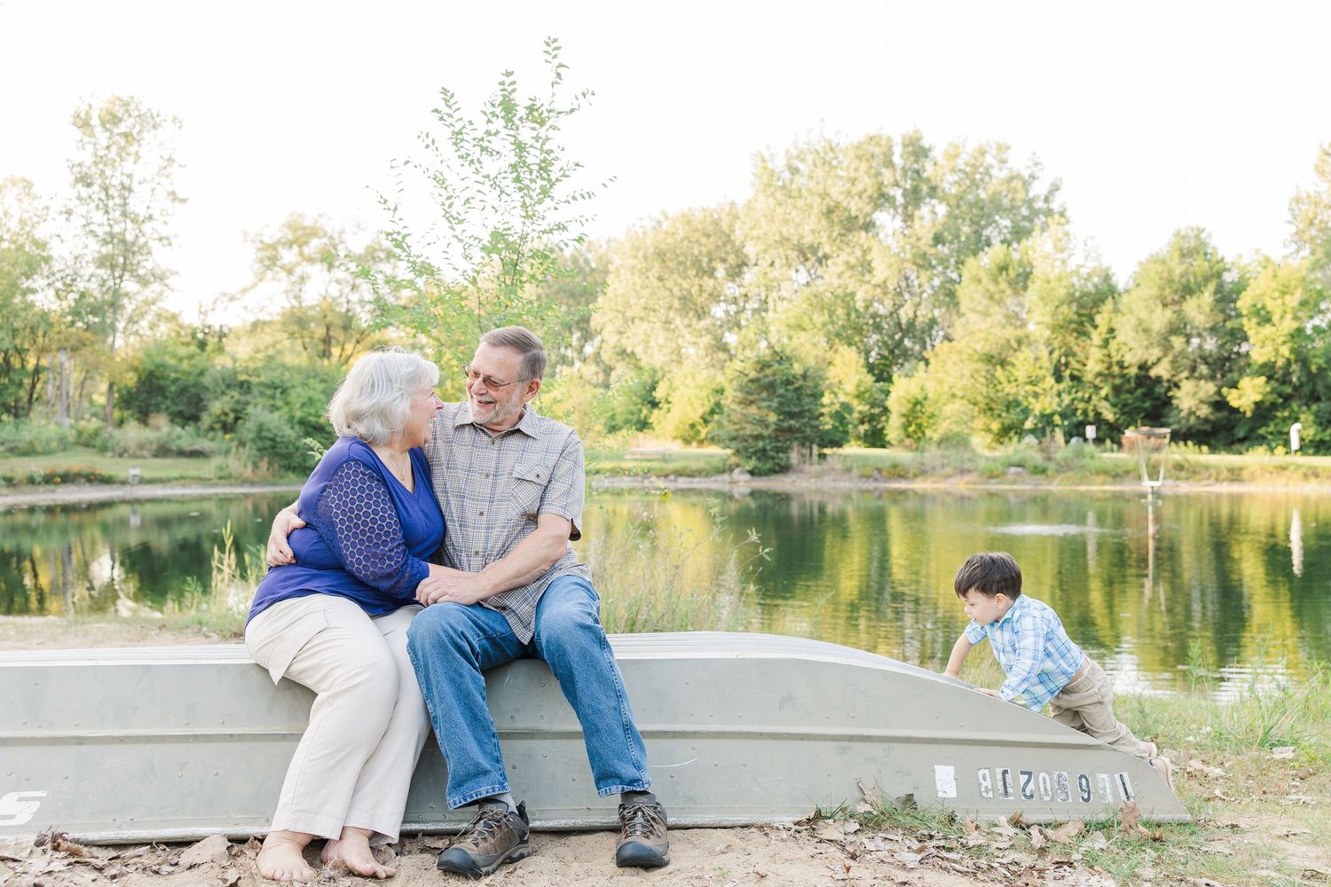 Couple sharing romantic moments by a serene lake during golden hour in a peaceful park setting.Sorg family portraits at Shamrock Hills Park