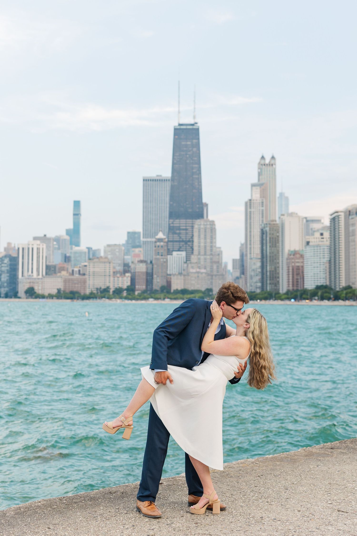 Elizabeth and Joe sharing a dip kiss with the Chicago skyline in the background at North Avenue Beach during sunset