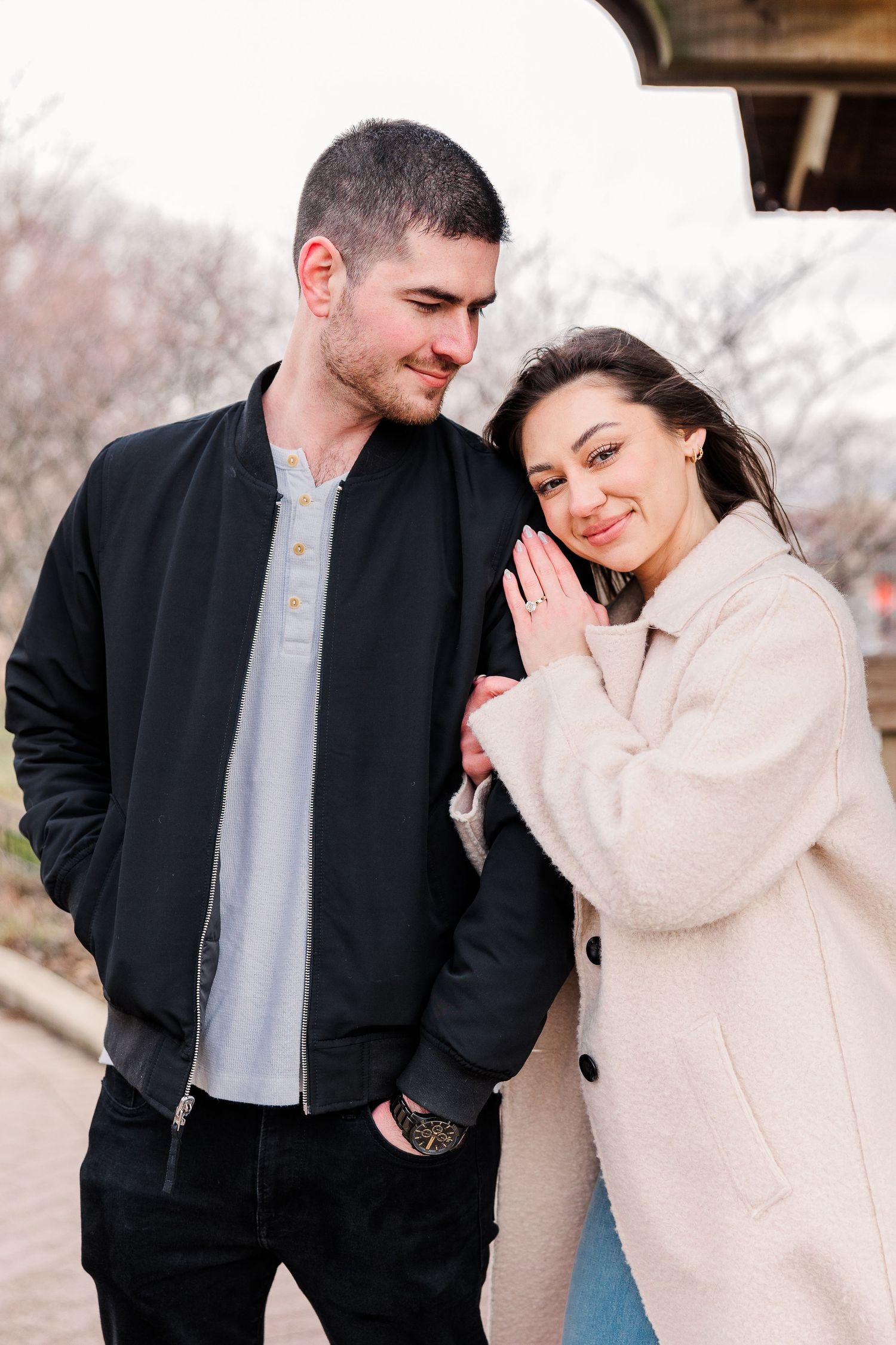 A couple in contrasting outfits sharing a warm embrace outdoors in winter.