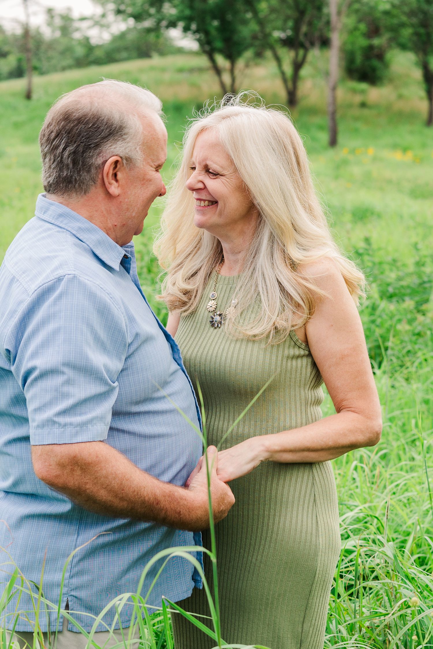 A romantic moment shared between a couple in a green summer meadow wearing casual attire.