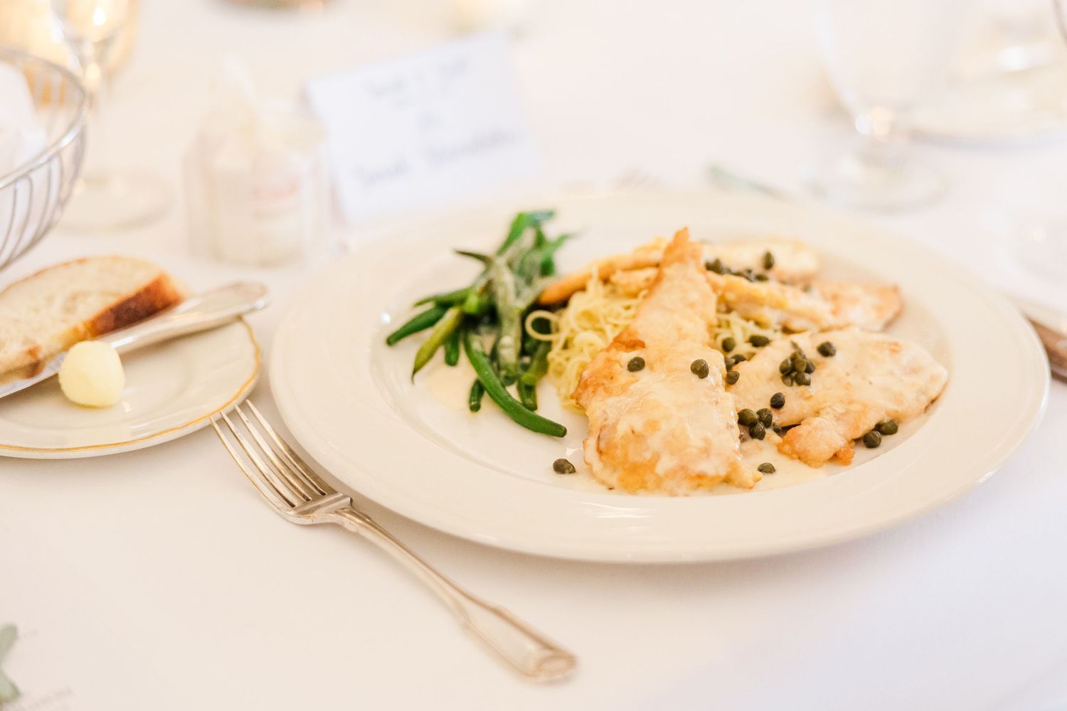 Elegant plated chicken dish with fresh herbs and vegetables on white china.