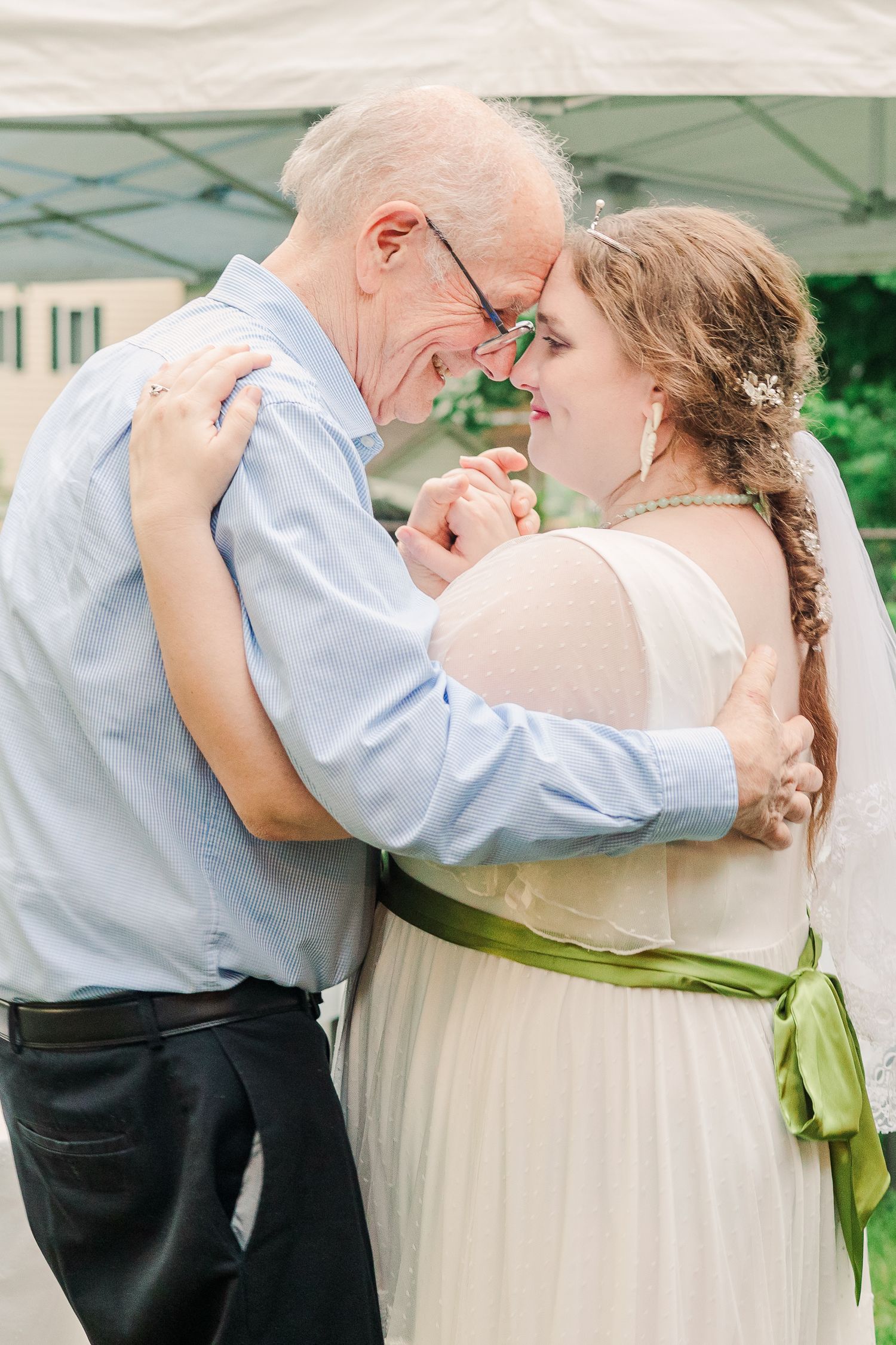 Tender moment during a wedding dance under a white tent.