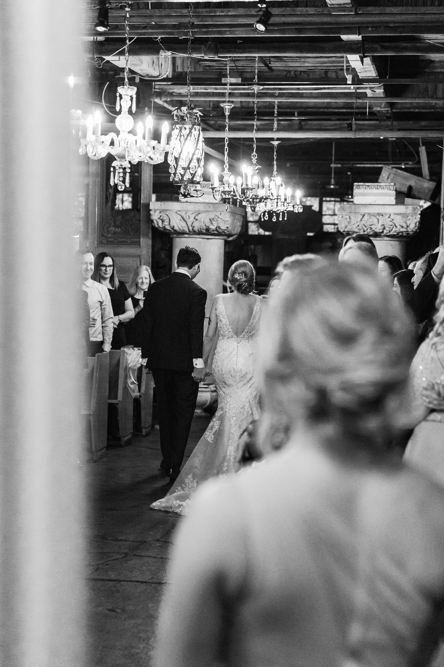 Wedding reception venue with hanging lights and guests in formal attire.