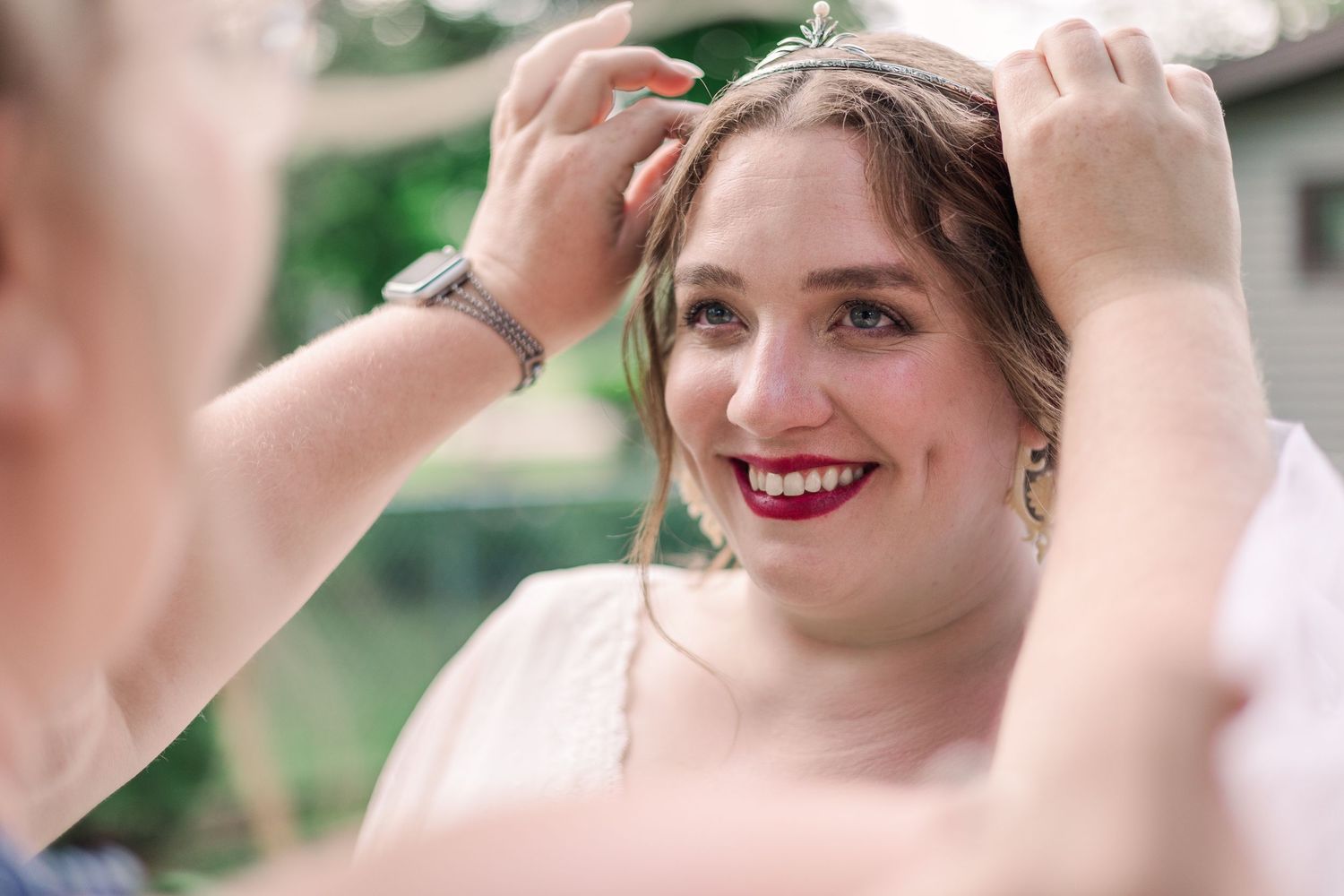 Person fixing hair while wearing red lipstick and formal attire.