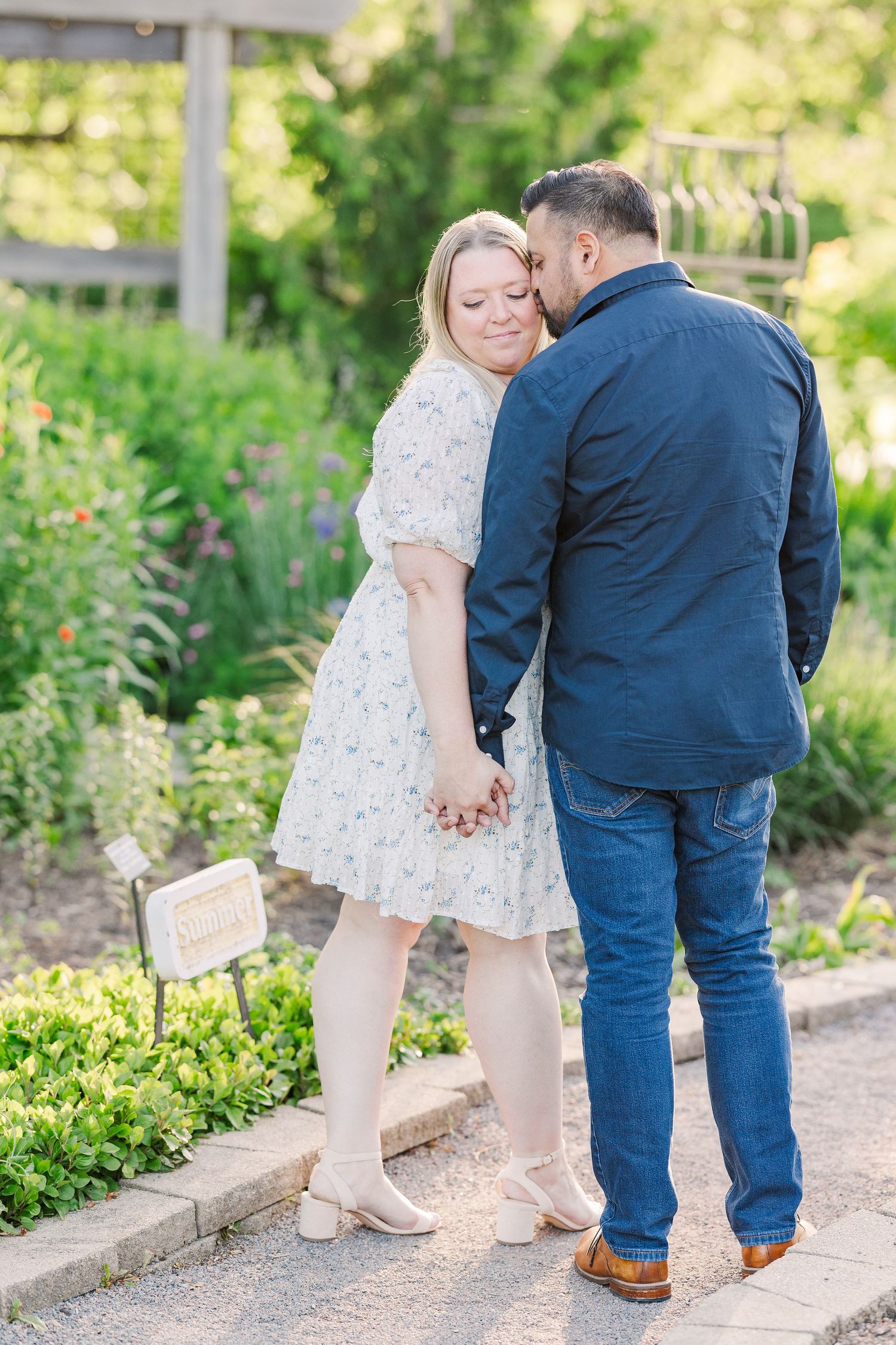 A tender moment captured between a couple on a garden pathway during their engagement shoot.