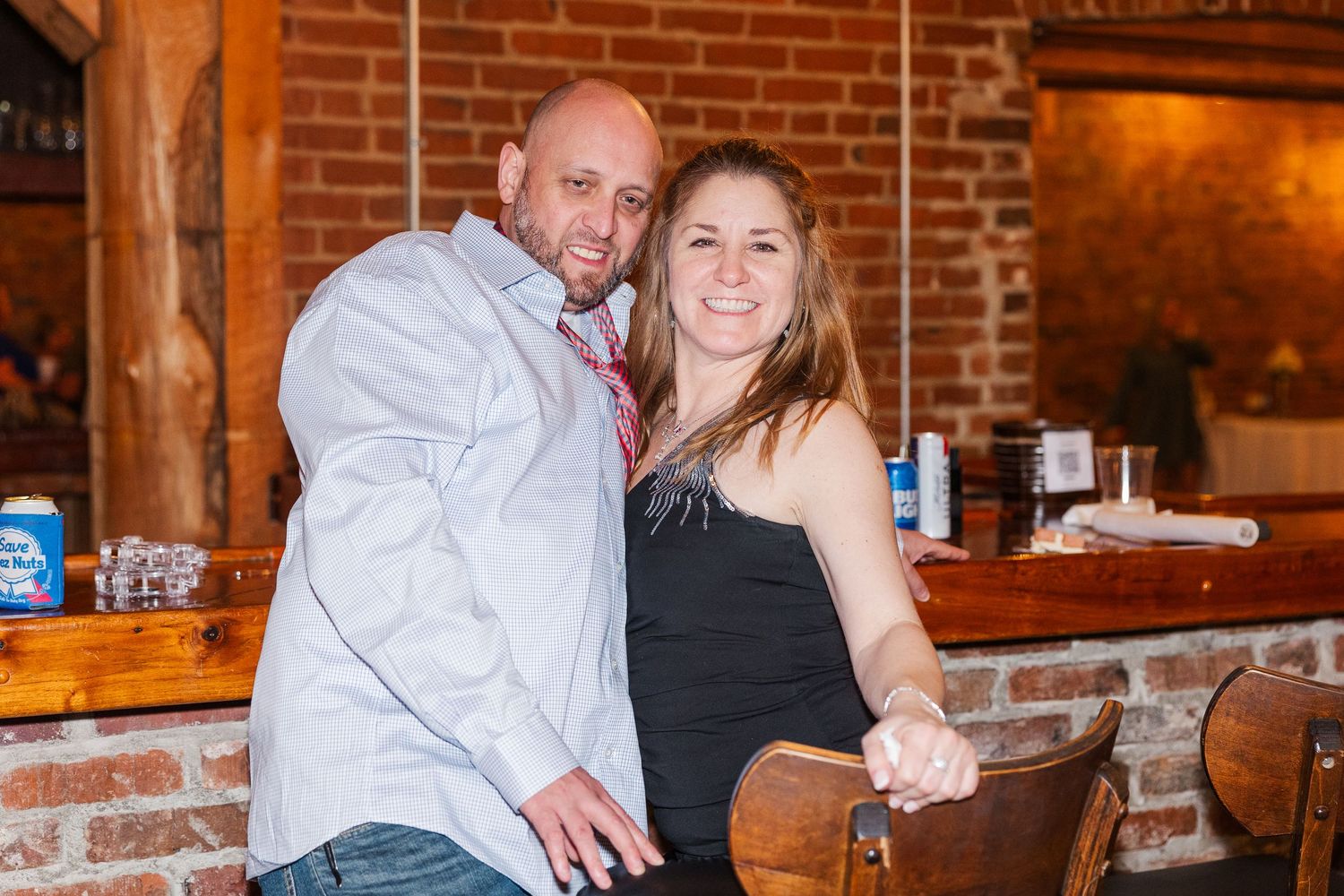 Couple posing together at rustic bar with exposed brick walls.