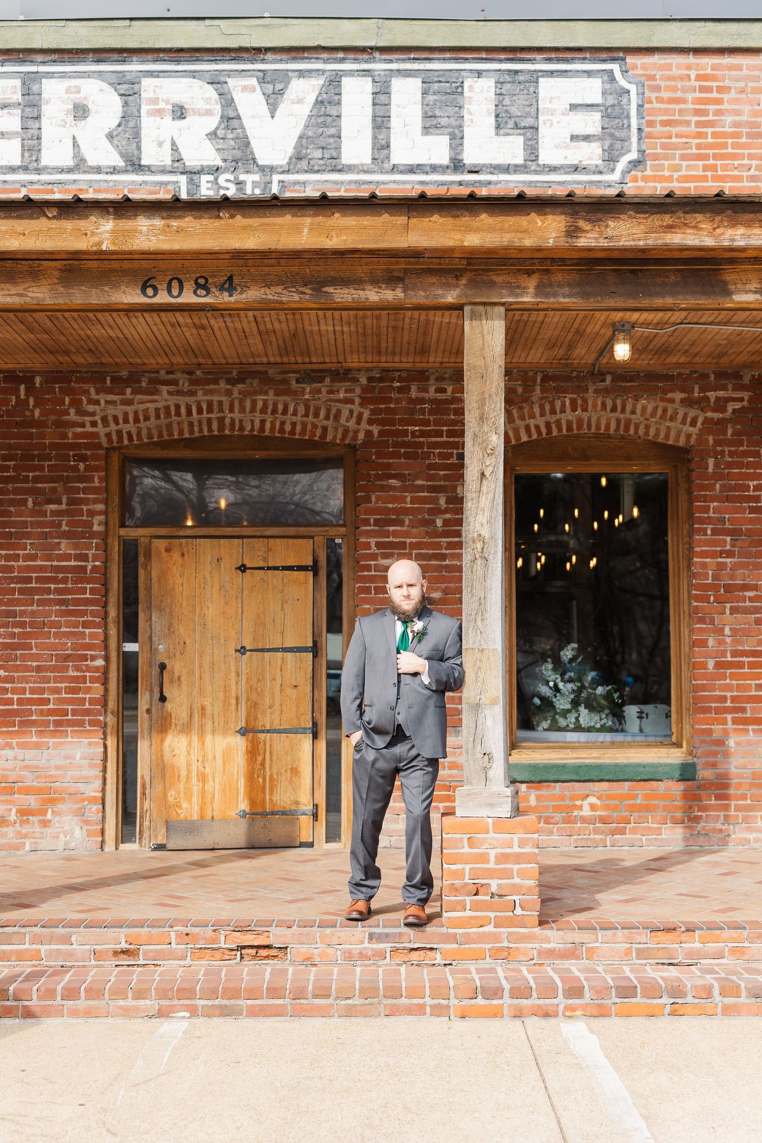 Person in grey suit standing outside historic brick building with Rrville signage.