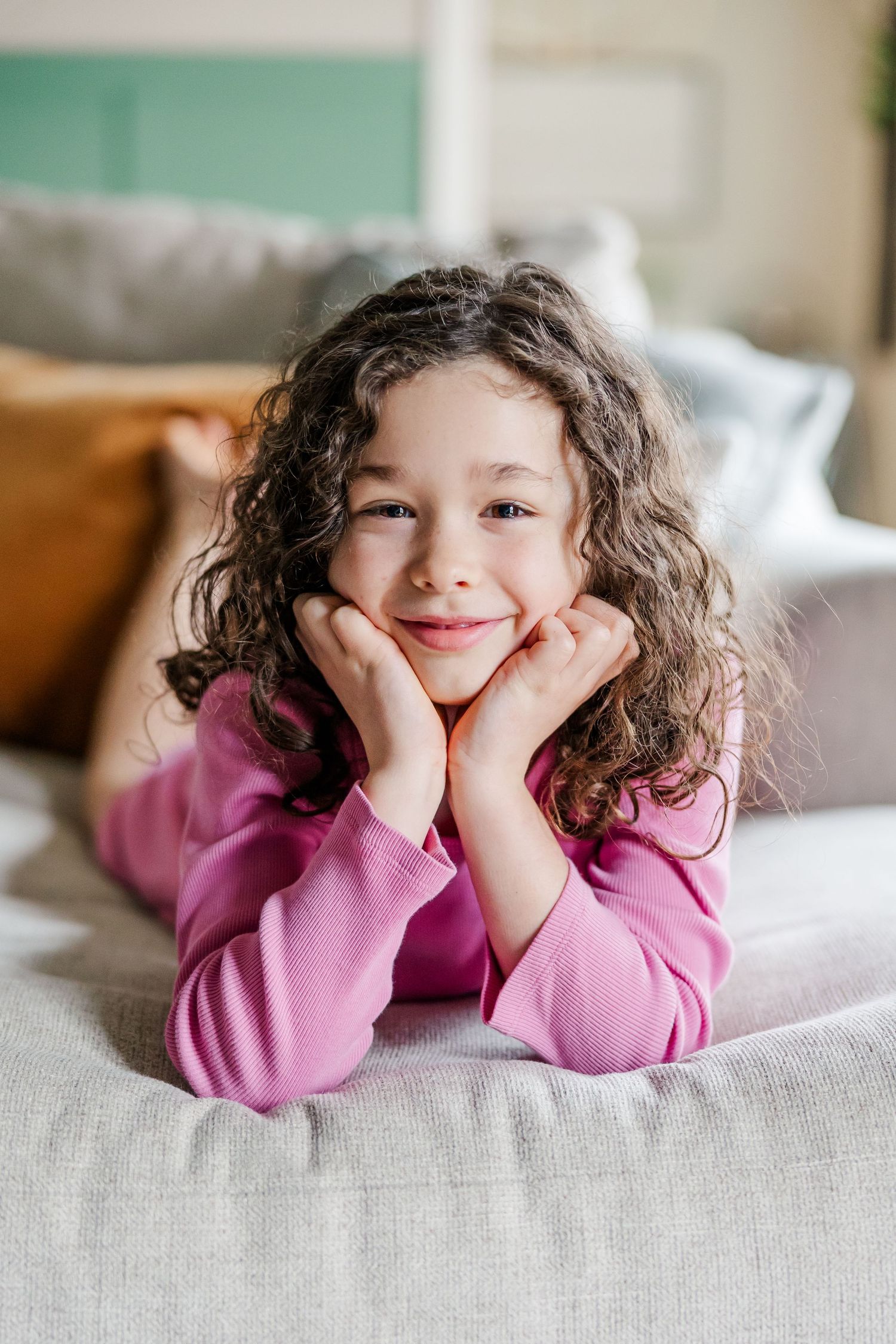 Big sister smiling on couch during in-home lifestyle newborn session in Crystal Lake, Illinois