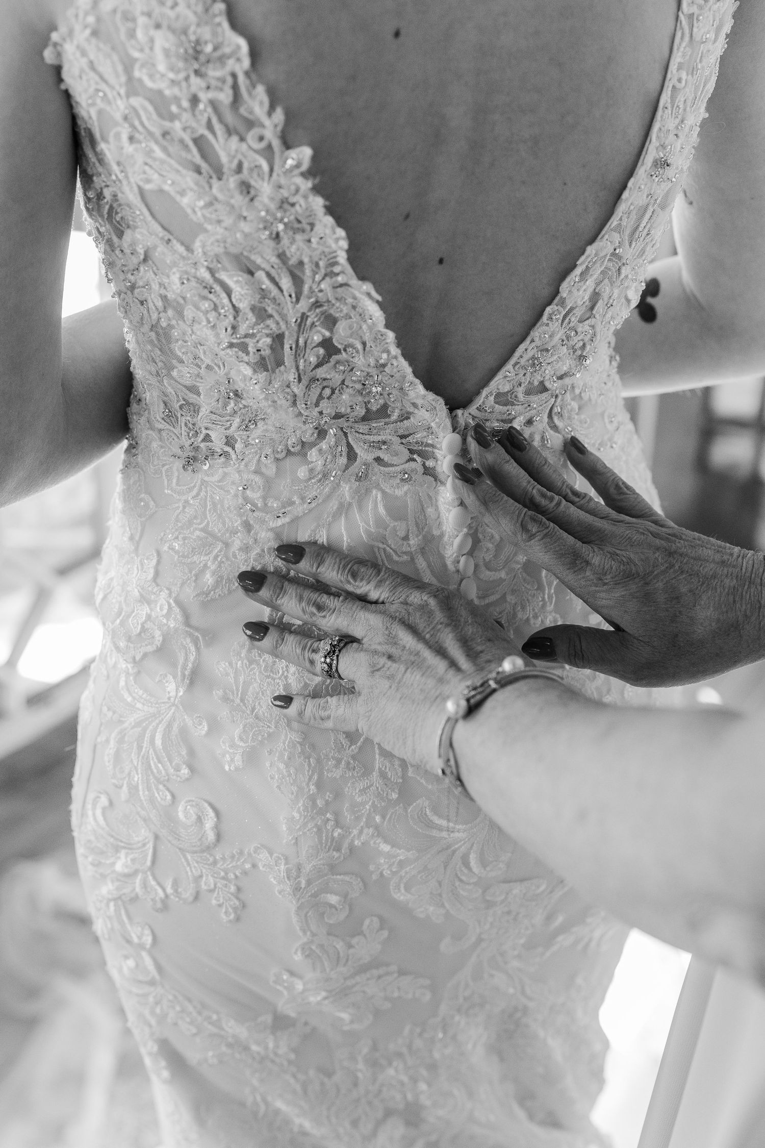Close-up black and white photo of intricate lace detailing on a wedding dress back.