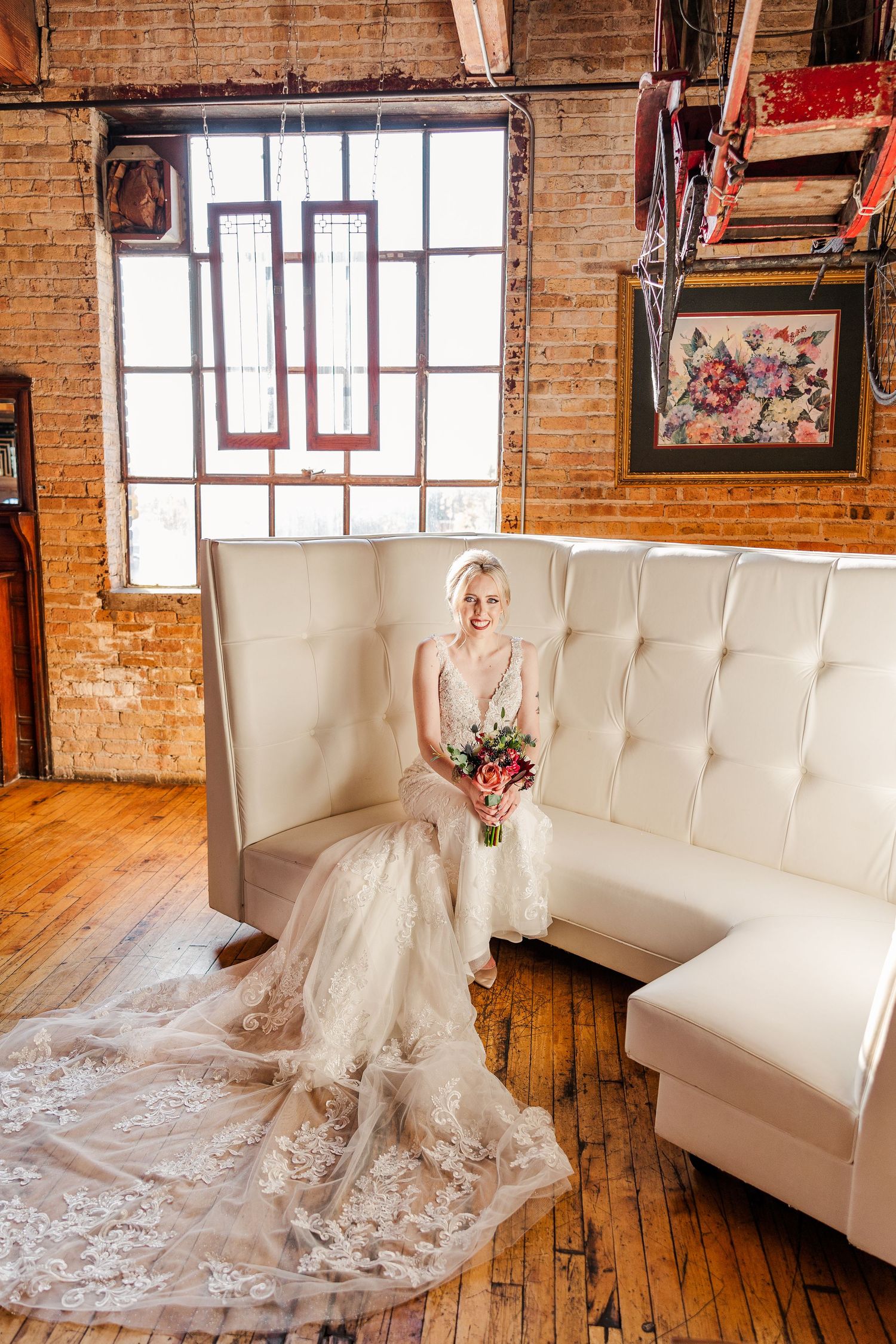 Wedding scene in rustic brick venue with white tufted couch and geometric window design.