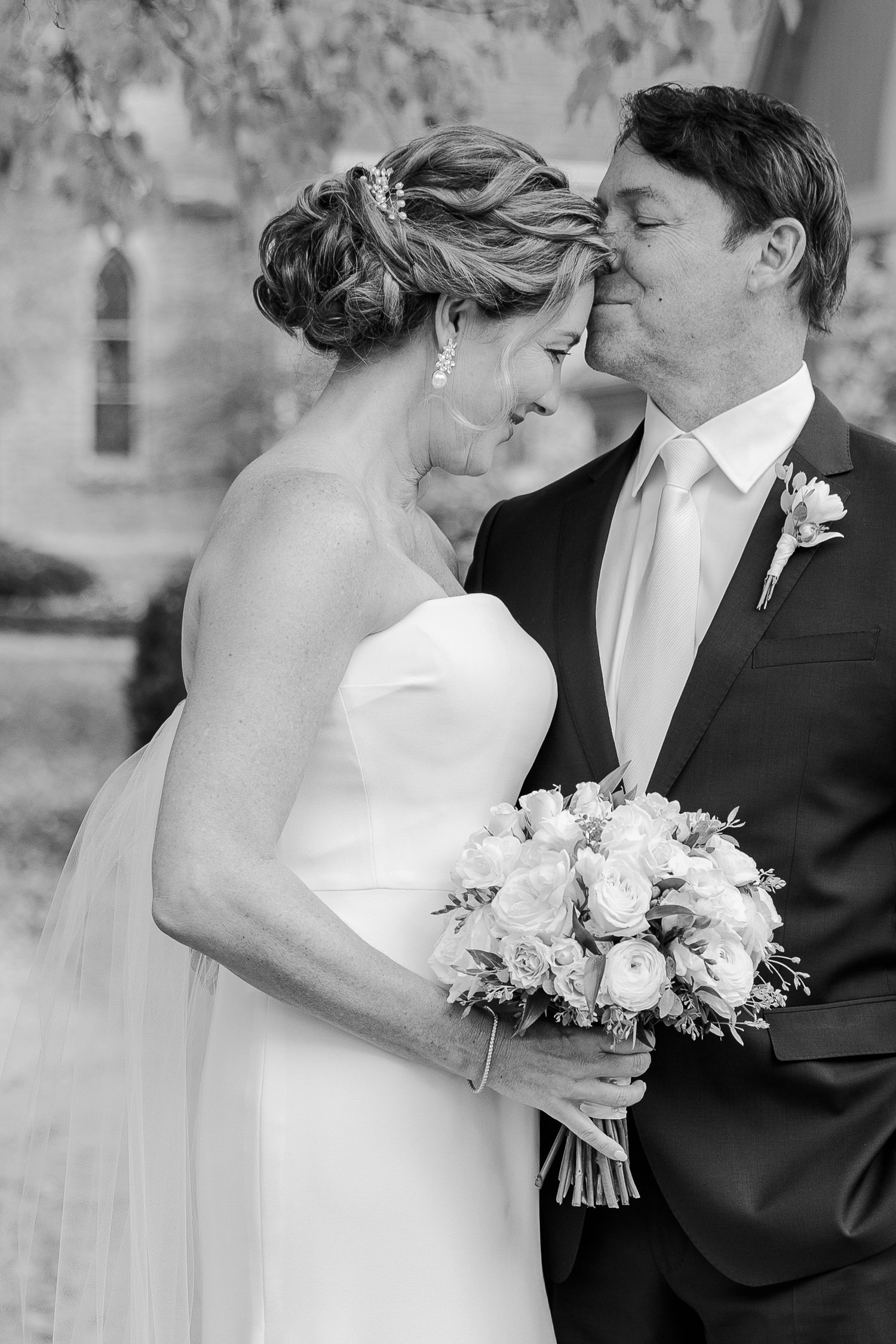 Intimate black and white portrait of newlyweds sharing a tender moment.