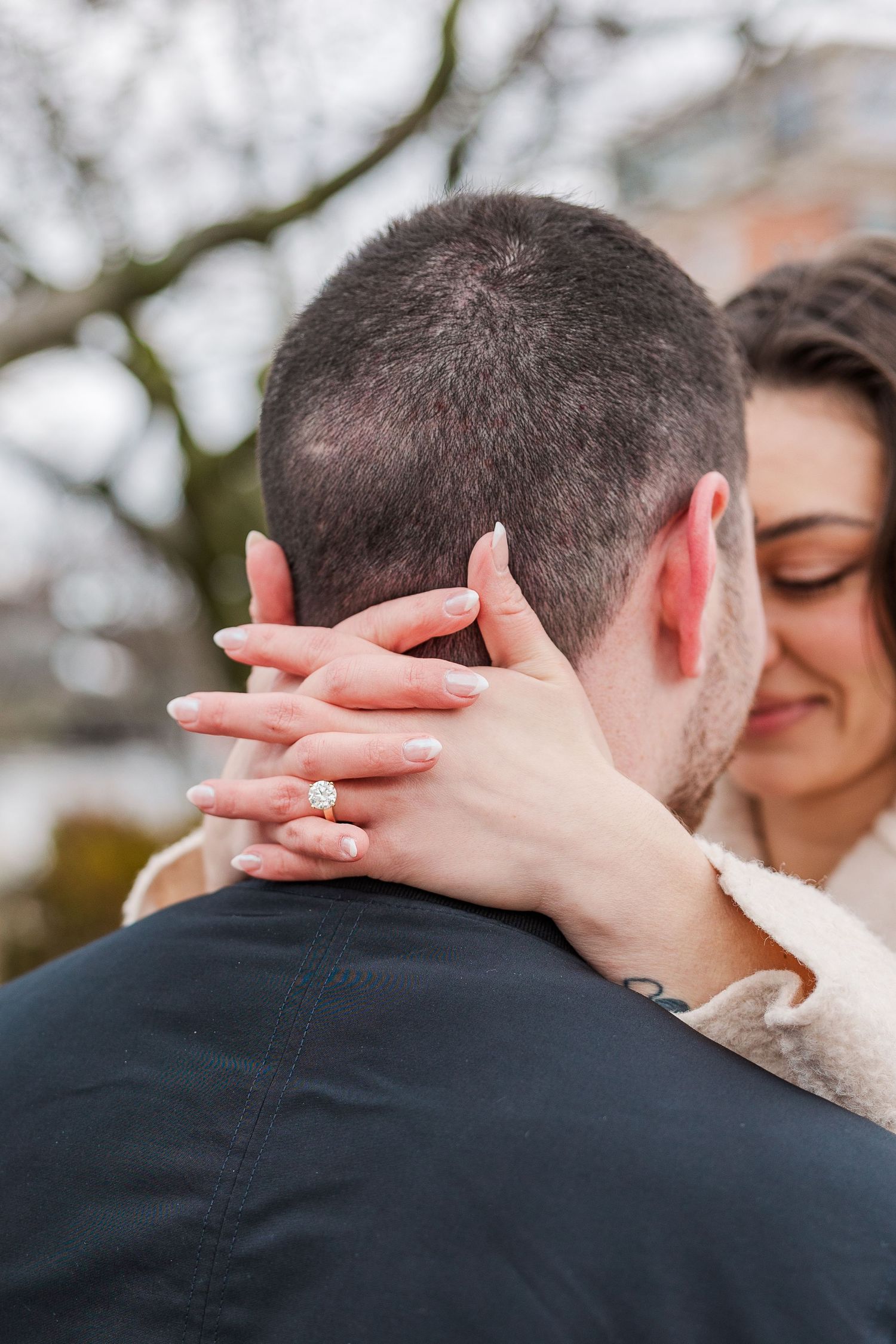 Close-up of hands with an engagement ring wrapped in an intimate embrace.