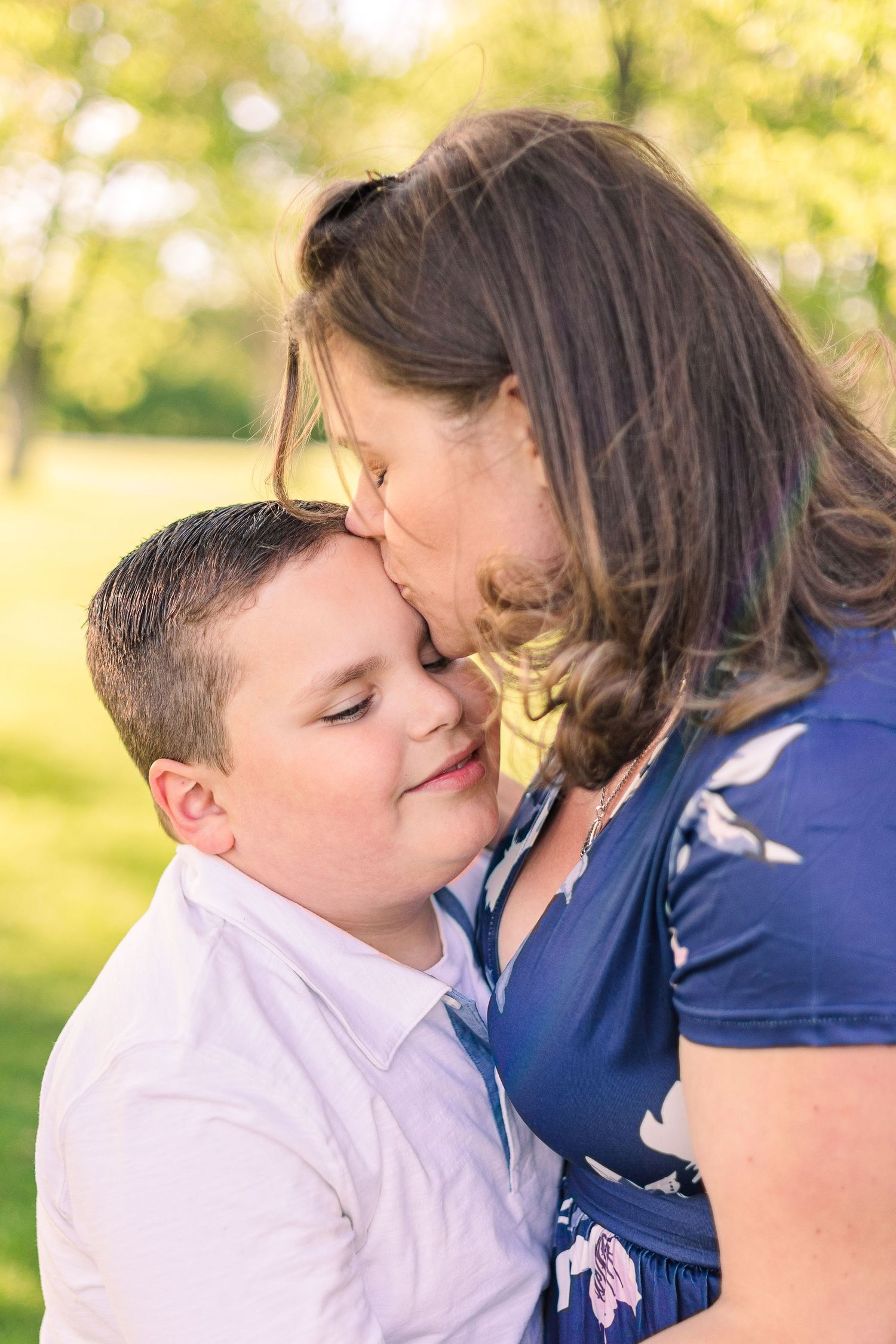 Intimate portrait showing affection between two people against a sunlit natural backdrop.