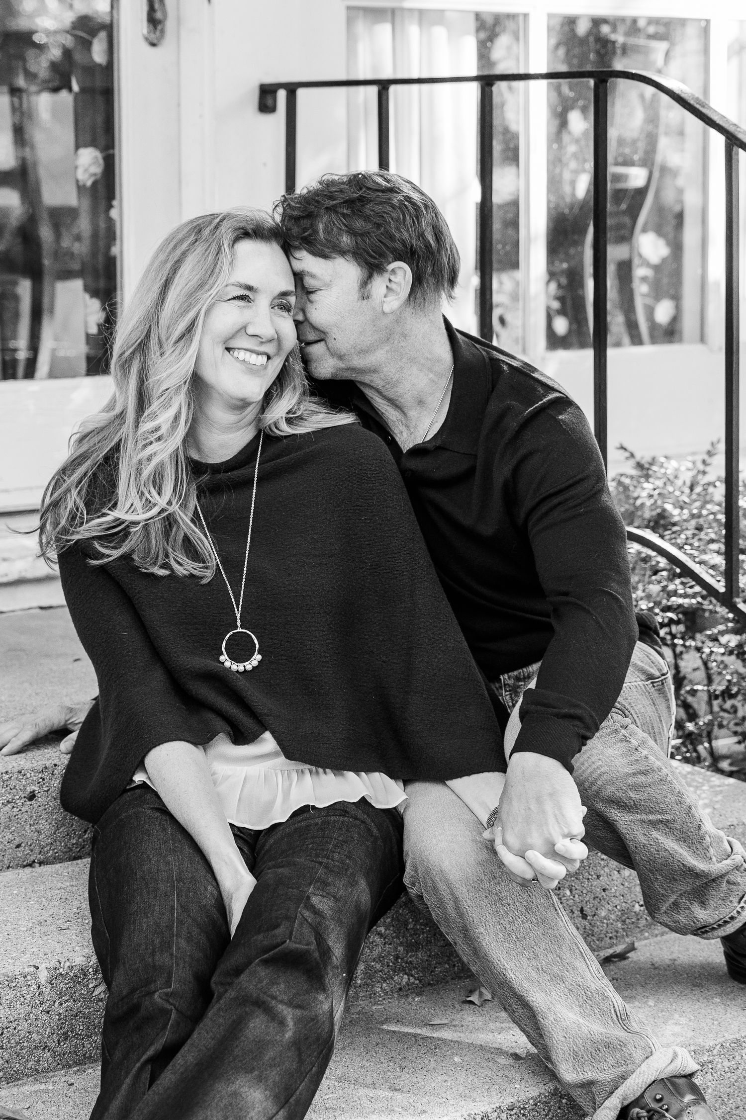 Black and white photo of couple sharing tender moment while sitting on outdoor steps.