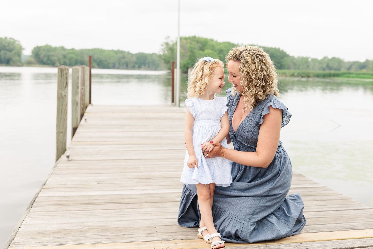 A tender moment shared on a wooden dock with a lake view in the background.